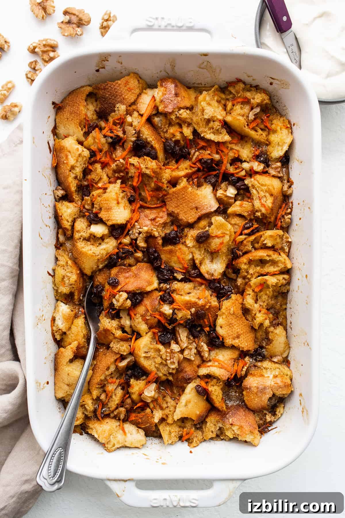 A spoon in a casserole dish of carrot cake french toast casserole.
