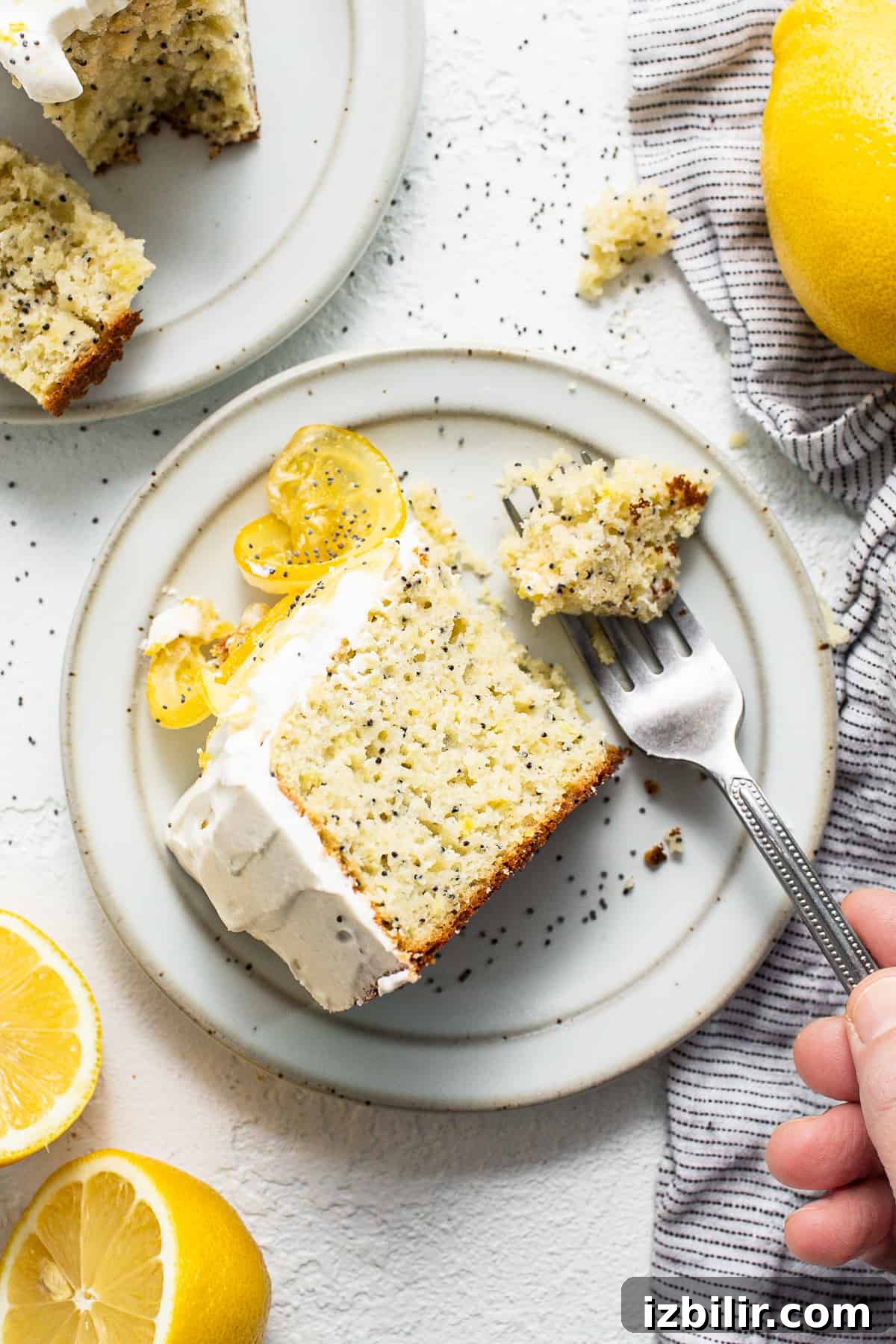 Slice of lemon poppy seed cake on a plate with a fork.