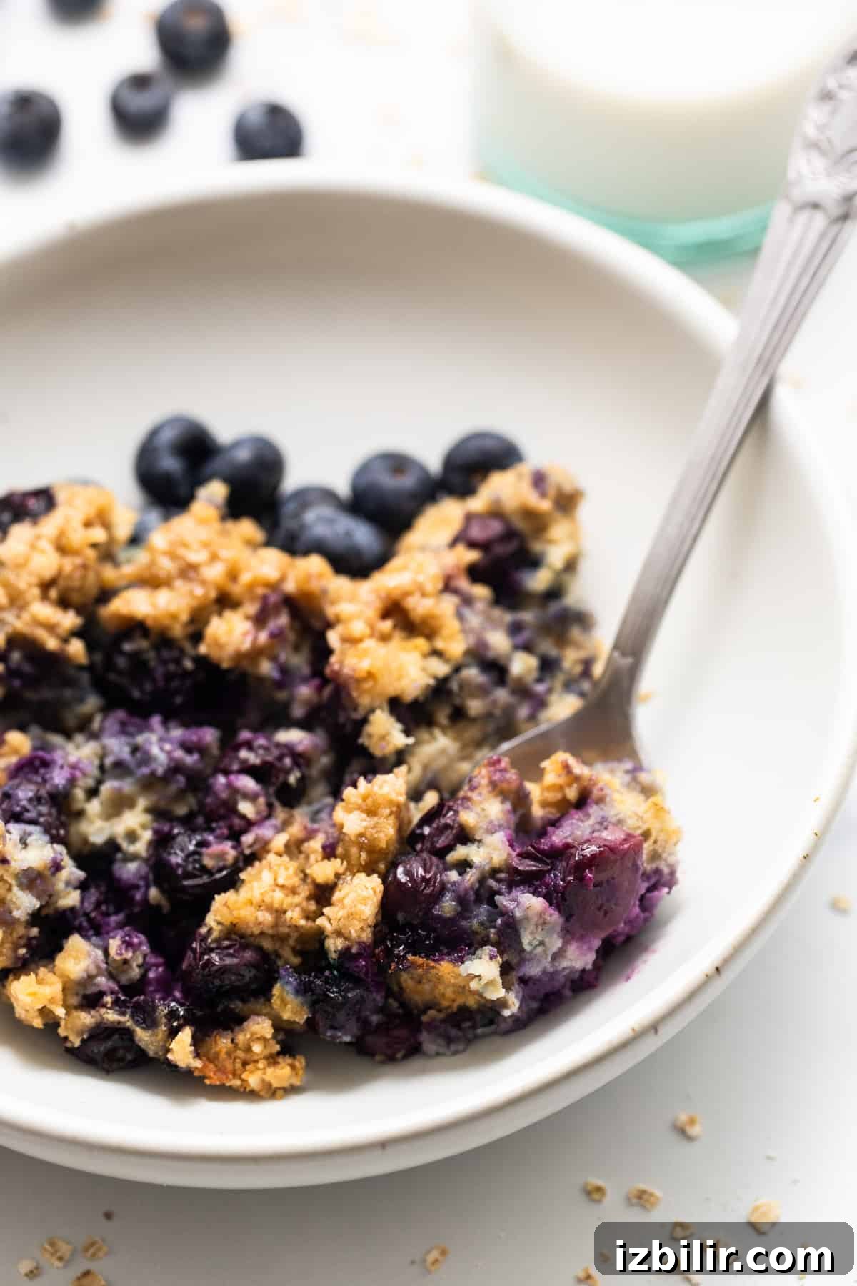 Blueberry muffin baked oatmeal in a bowl with a spoon.