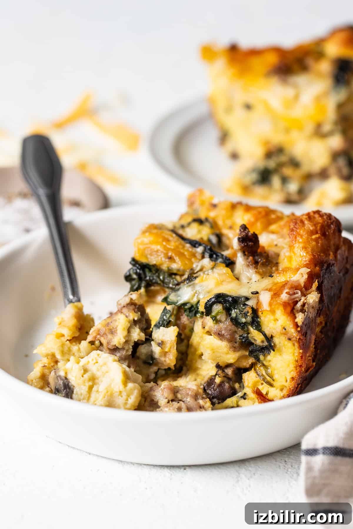 Slice of breakfast strata on a plate with a fork.