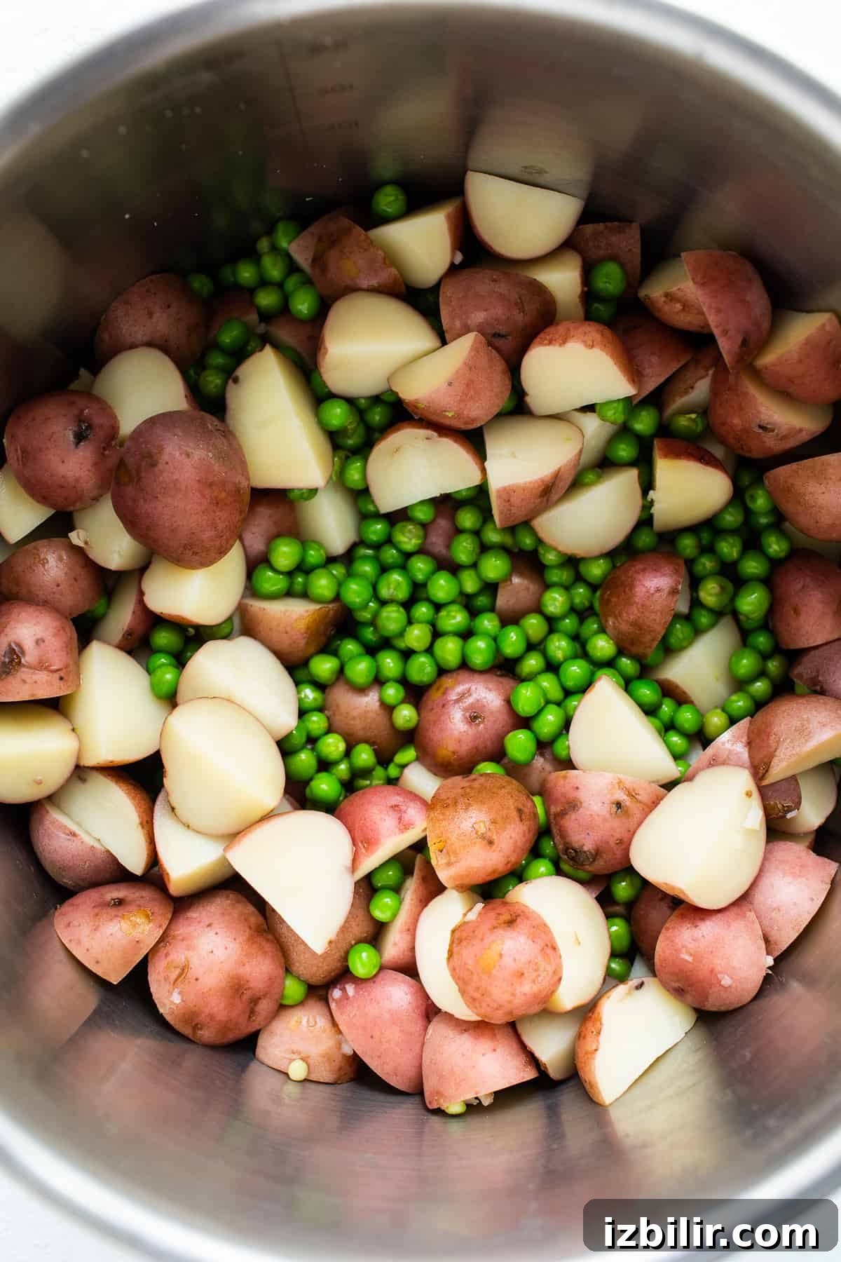 Red potatoes and english peas in a metal bowl.