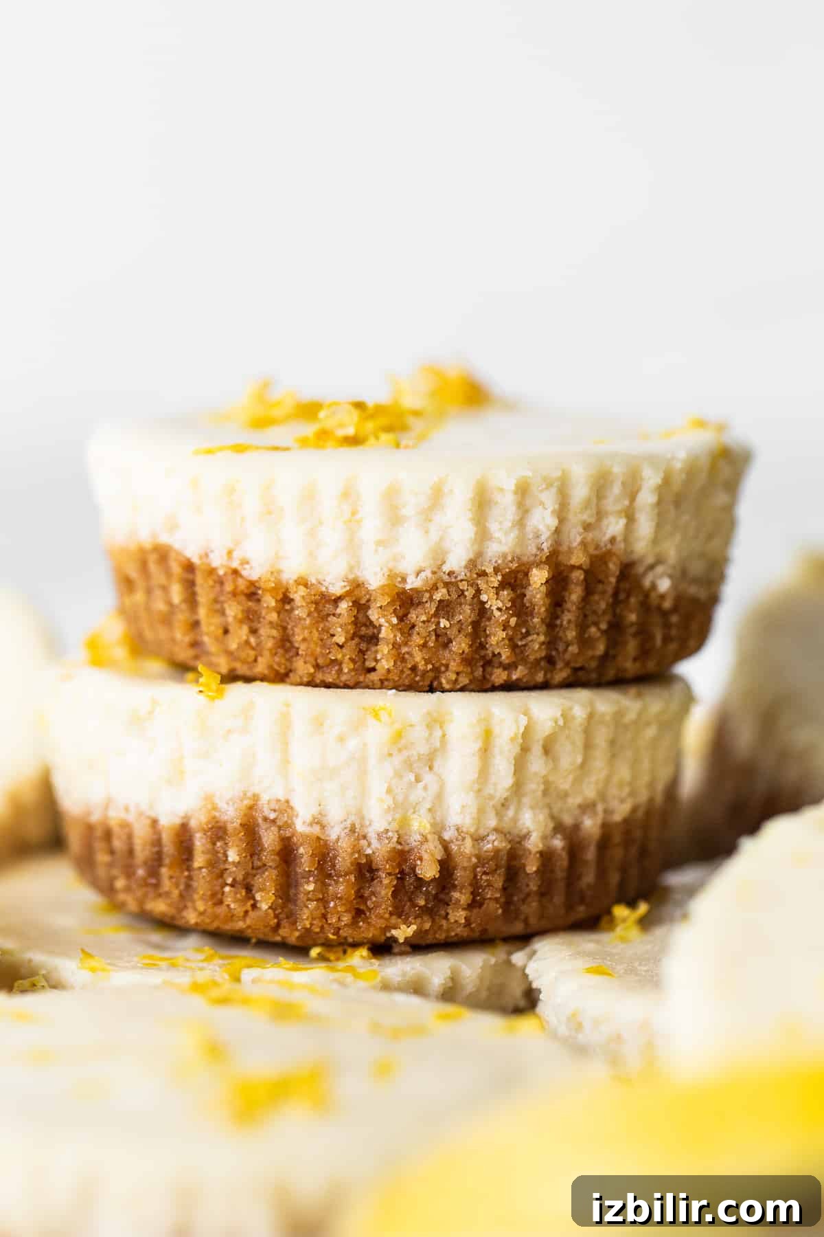 This mini cheesecake recipe is made with a sweet and salty crust, cream cheese, honey, vanilla, and lemon zest making them the perfect Spring dessert. stack of cheesecakes.