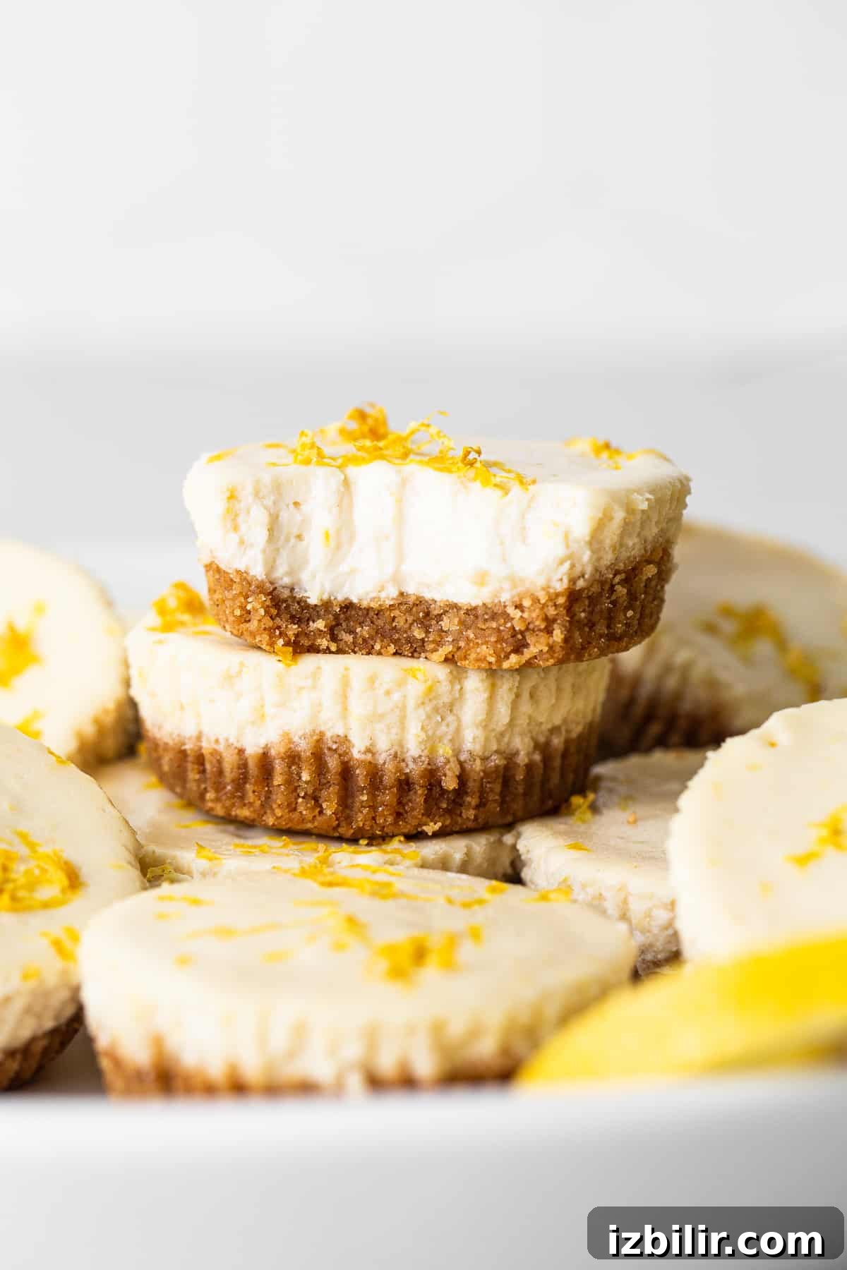 This mini cheesecake recipe is made with a sweet and salty crust, cream cheese, honey, vanilla, and lemon zest making them the perfect Spring dessert. stack of cheesecakes.