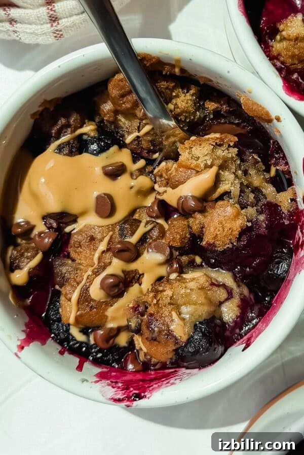 Mini Lemon Cheesecake Bites Recipe 2 A bowl of berry crumble topped with peanut butter, chocolate chips, and a spoon resting inside.