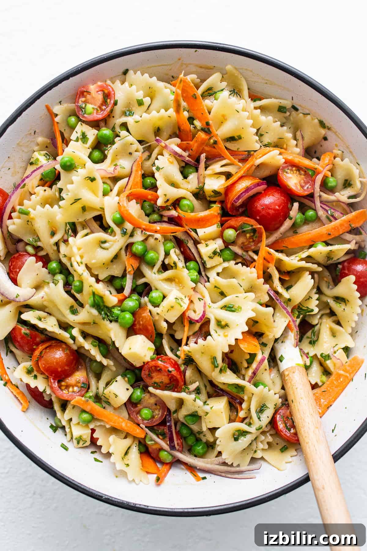 Bow tie pasta salad in a bowl with a spoon.