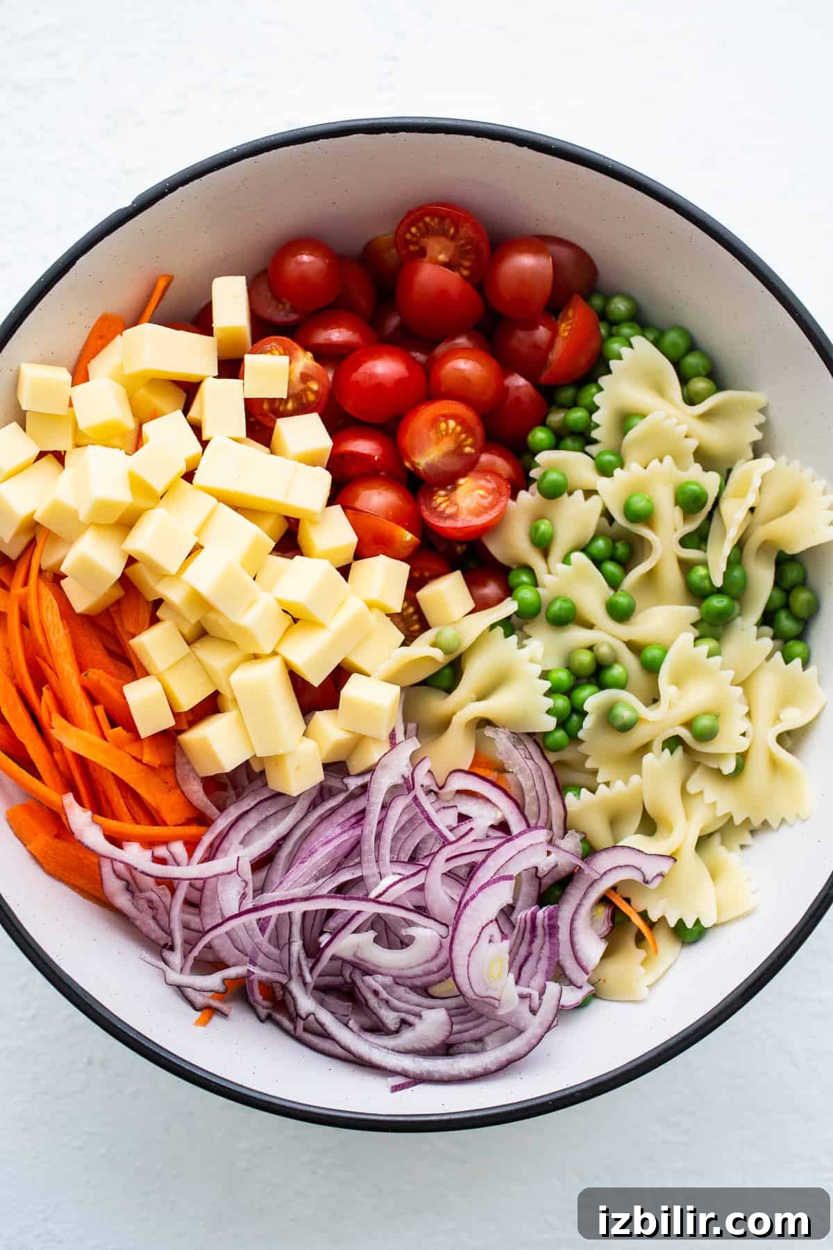Bow tie pasta salad ingredients in a bowl.