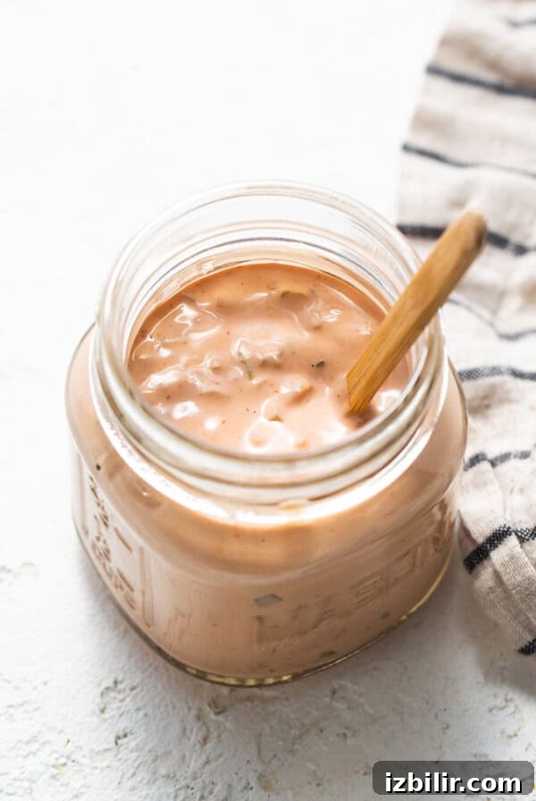 A jar of ketchup with a wooden spoon.