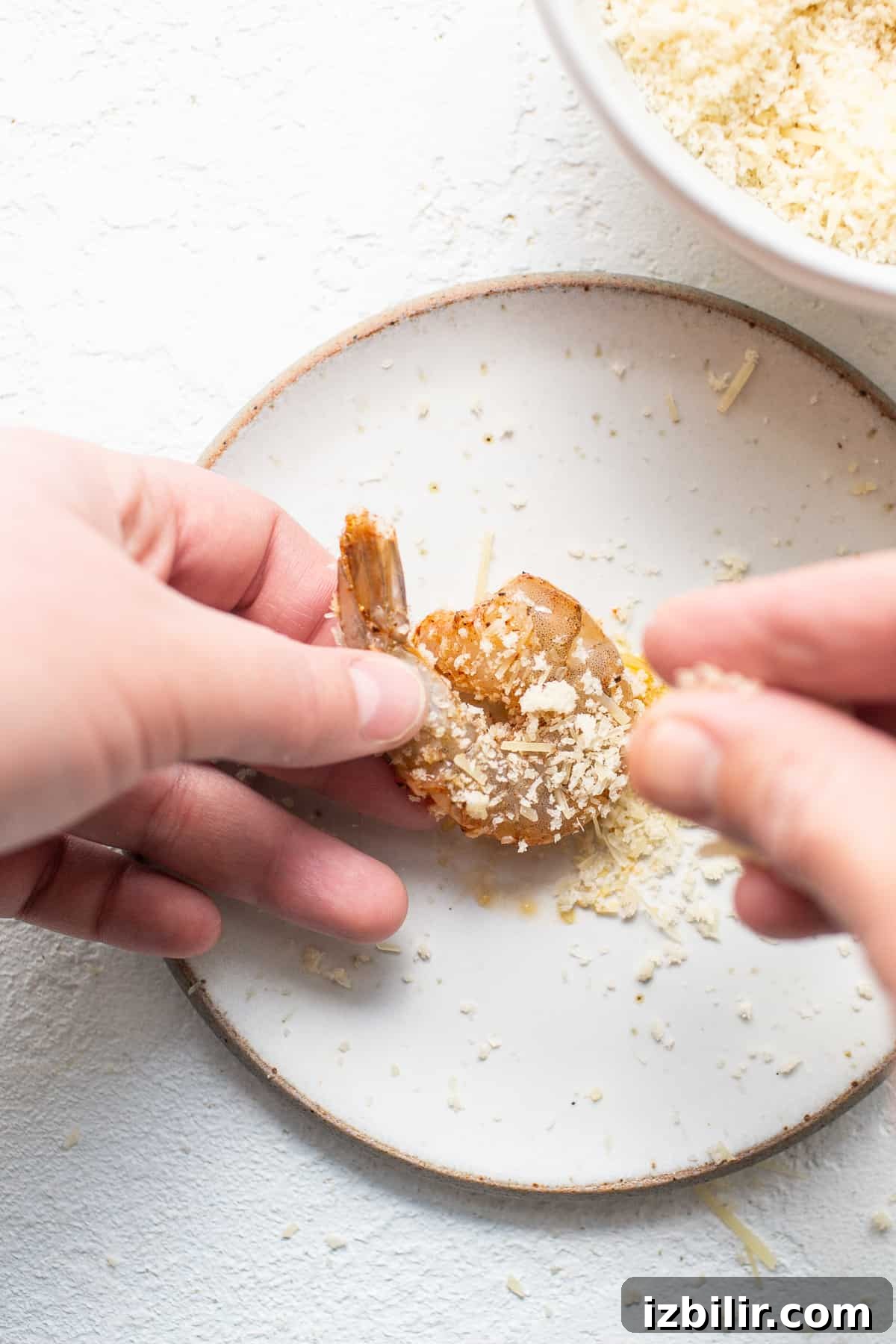 Shrimp being breaded with panko and parmesan.