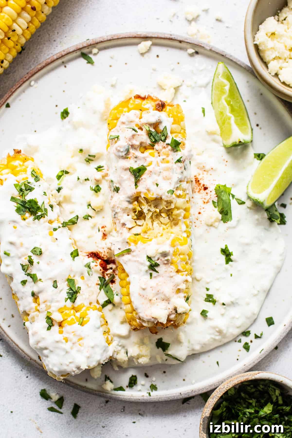 Air fryer elote with a bite taken out of it on a plate.