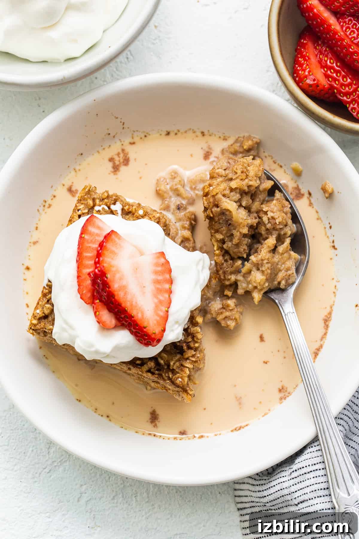 Tres Leches Baked Oatmeal Slice of tres leches baked oatmeal in a bowl topped with strawberries.
