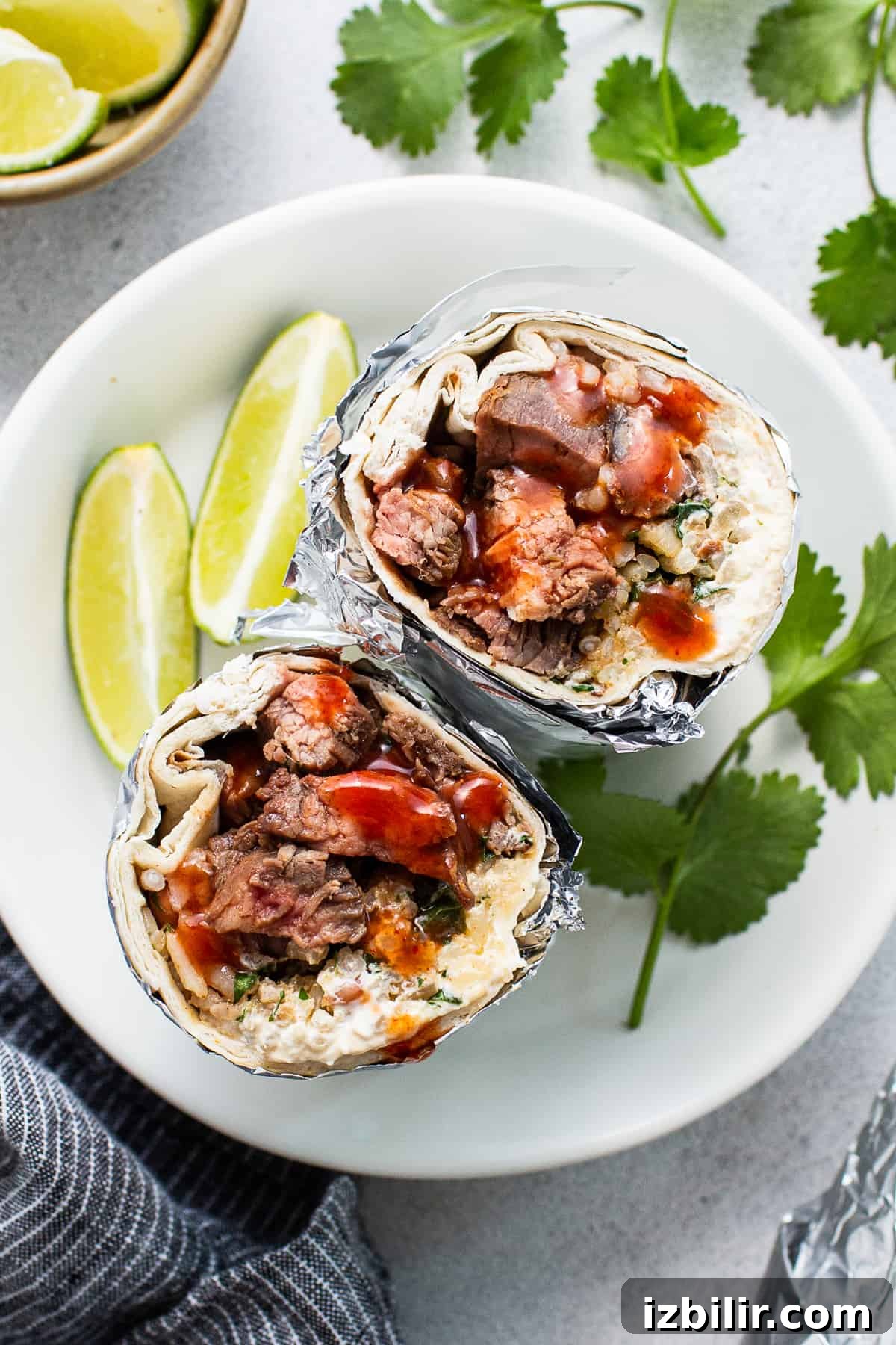 Steak burrito on a plate wrapped in foil.