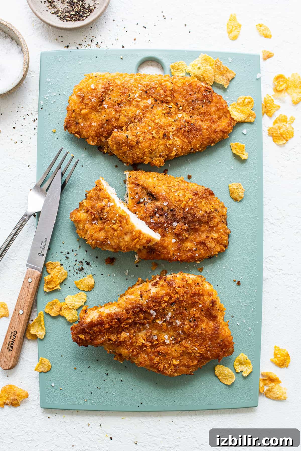 Crispy pan-fried chicken breast with cornflake coating Chicken breast on cutting board.