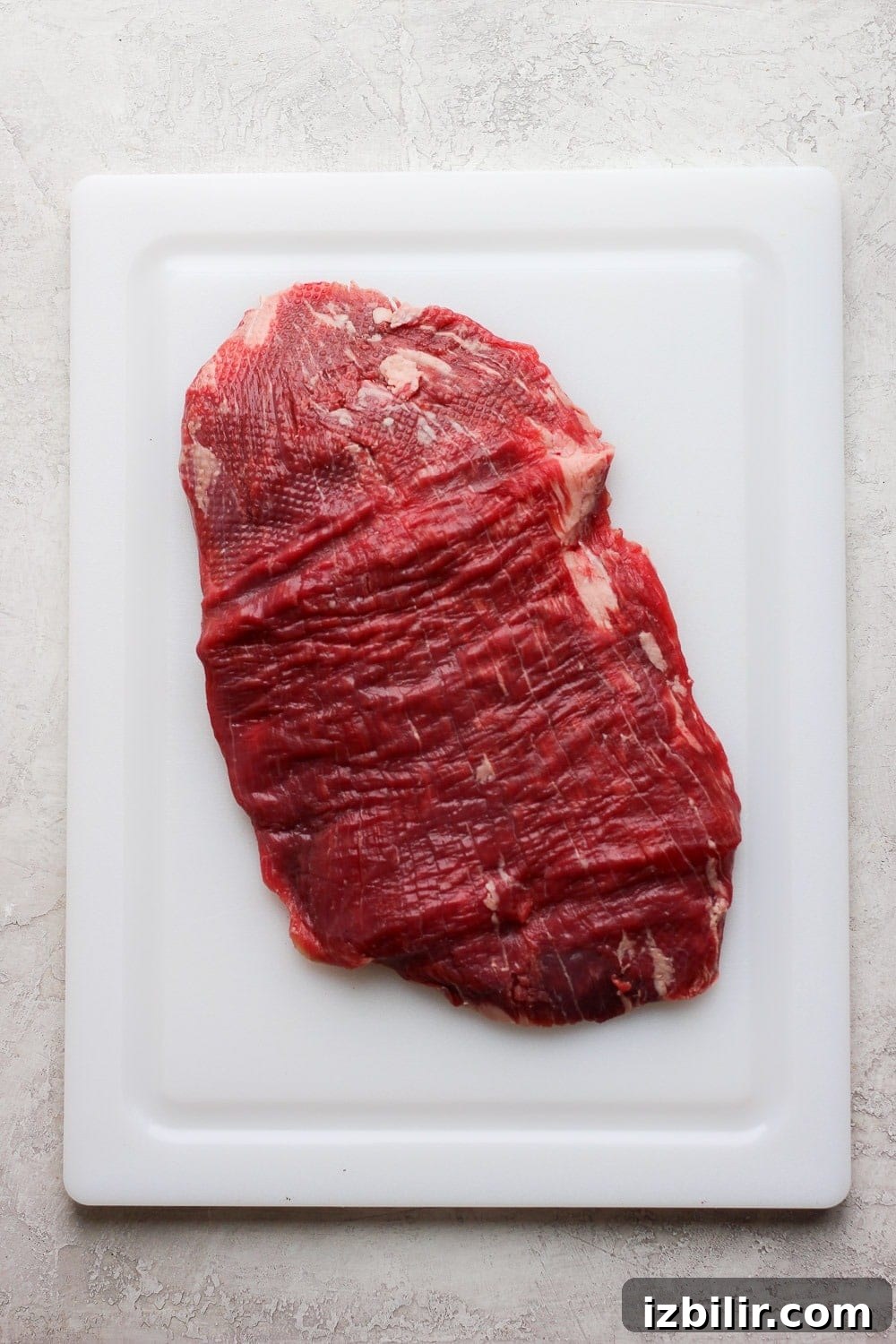 Flank Steak Marinade for Grilling and Searing 4 Raw flank steak on a cutting board.