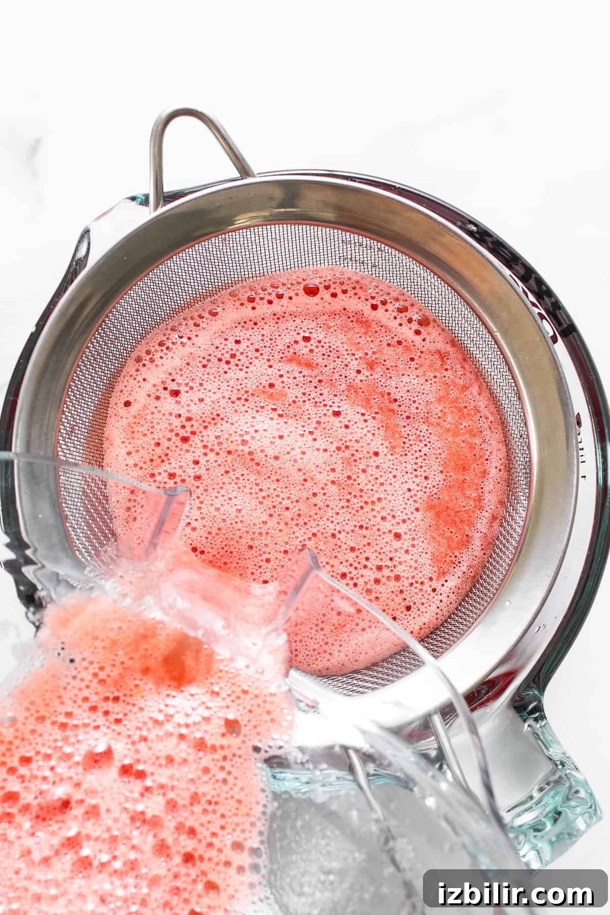 Sieving watermelon juice to remove pulp and seeds.