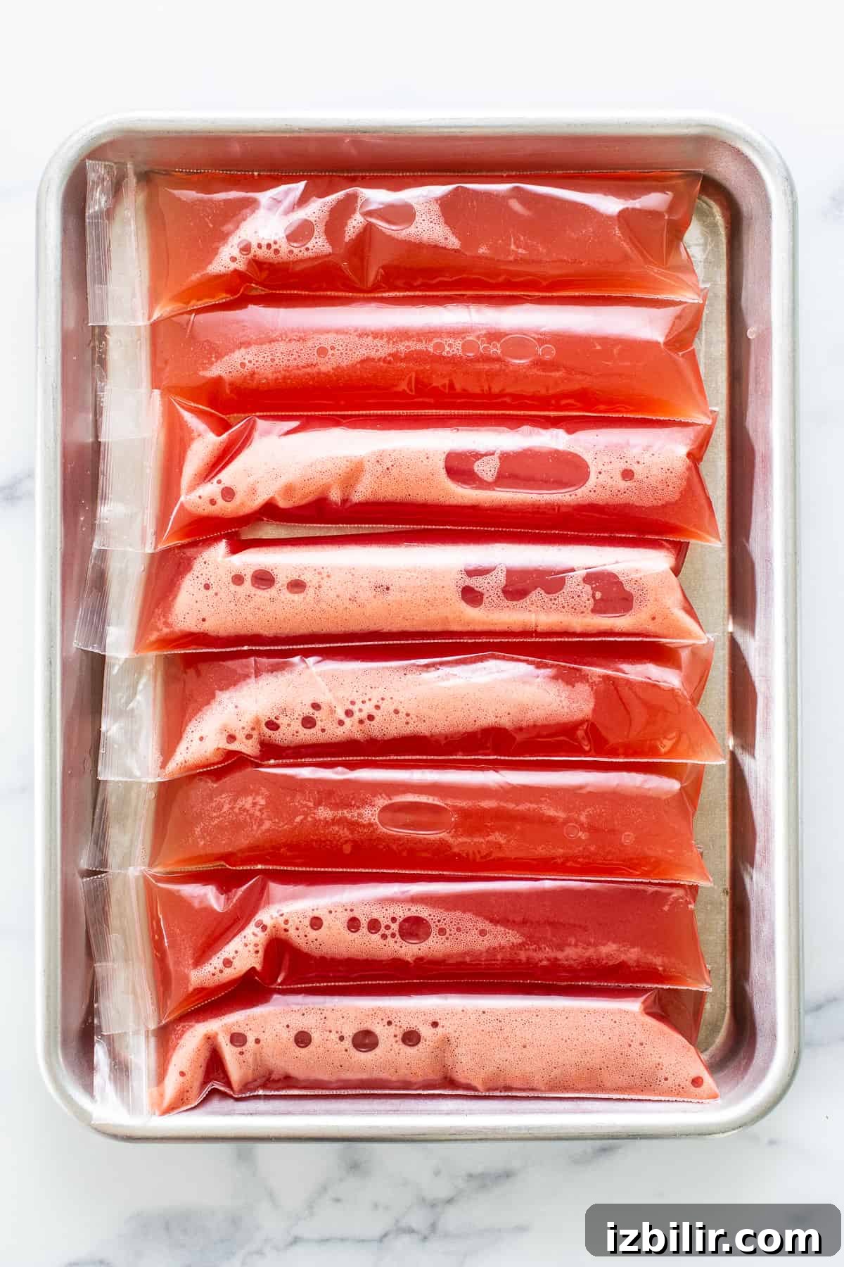 Watermelon wine freeze pops placed on a baking sheet before freezing.