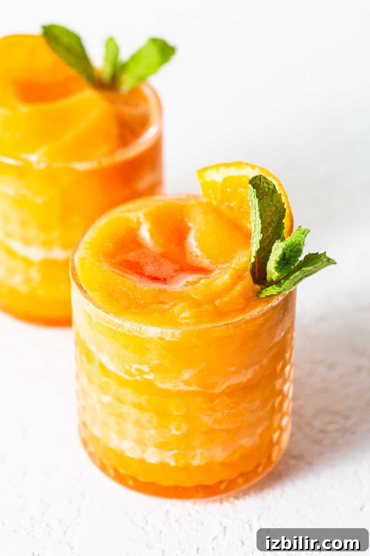 Frozen Aperol Spritz Slushies are the drink of the summer. Use frozen clementines to make it extra slushy and don't forget the Aperol and champagne. slushy in glass.