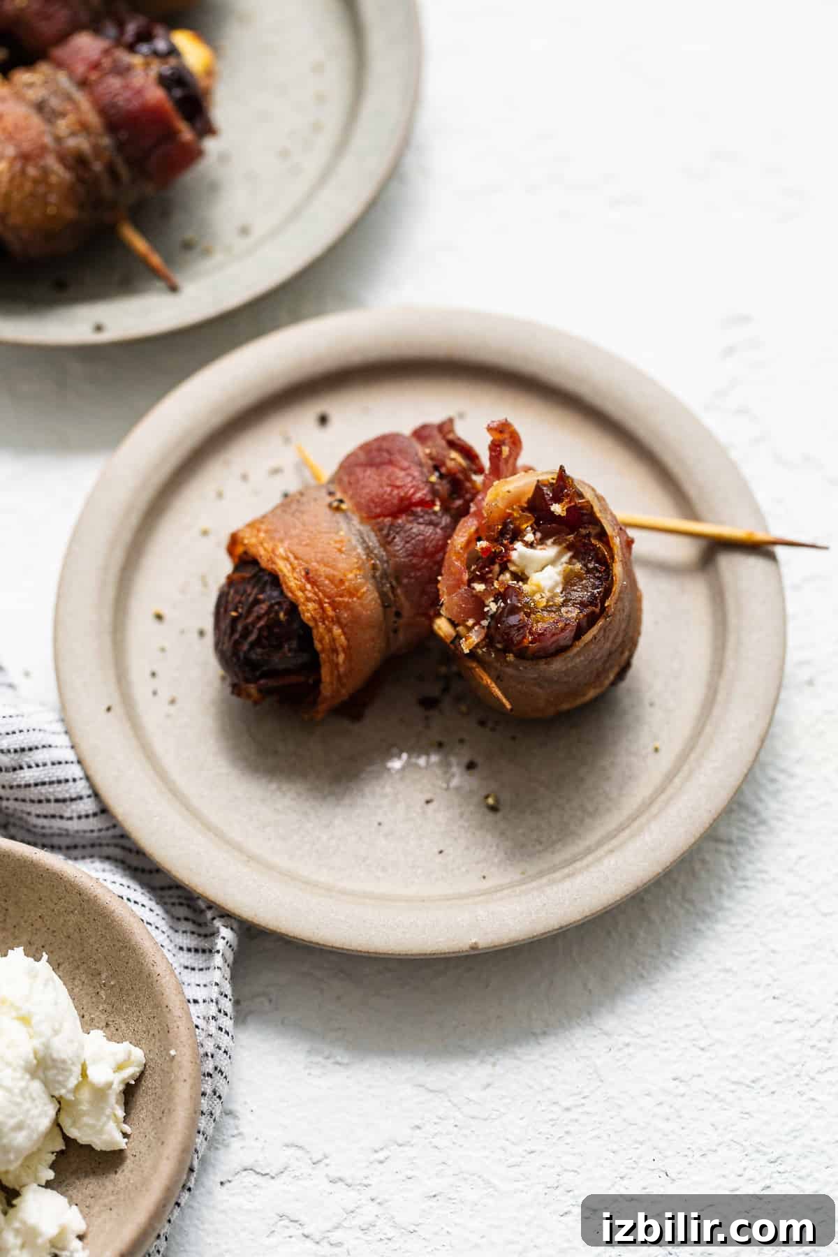 Bacon wrapped dates ready to serve Bacon wrapped dates with goat cheese on a plate.