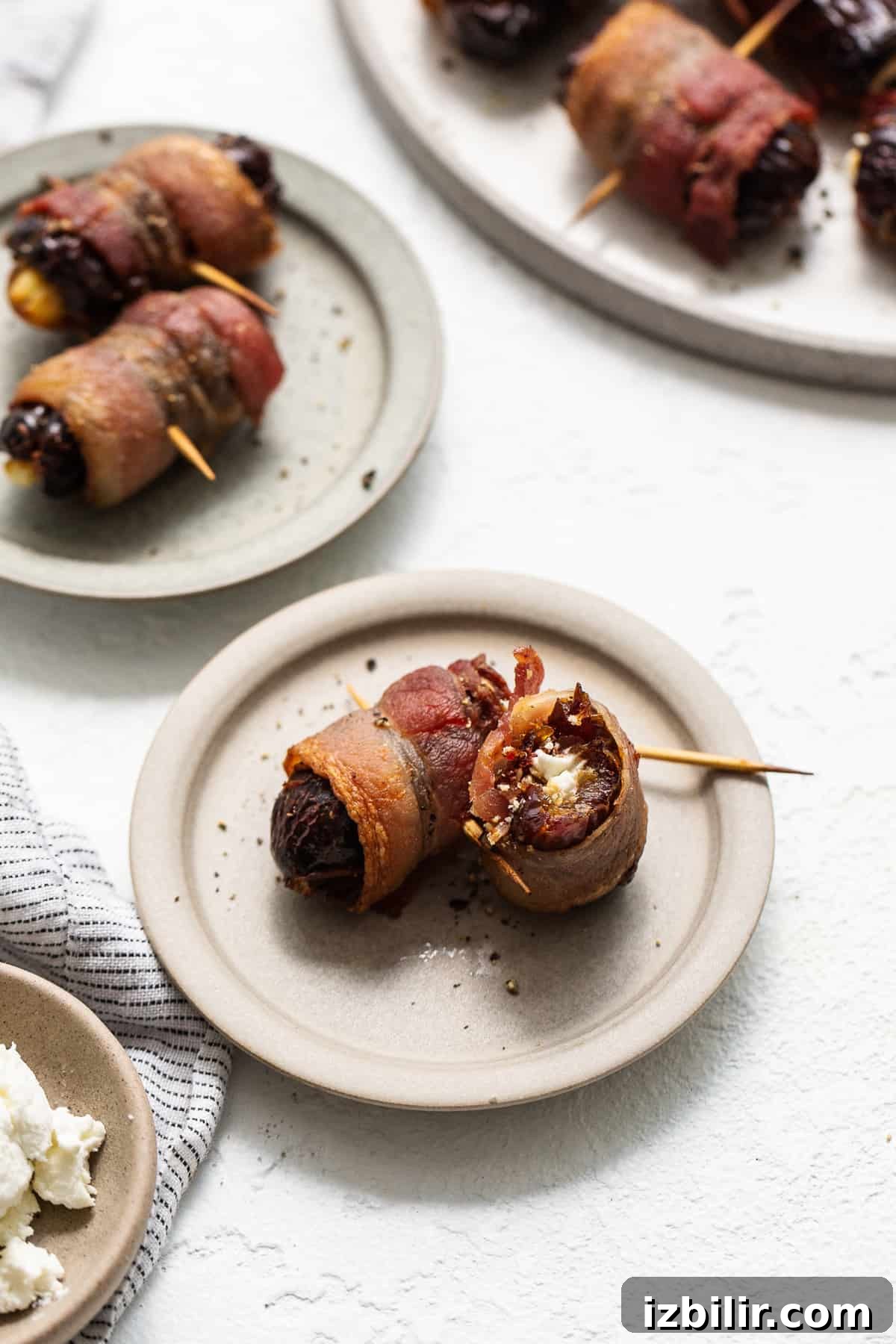 Serve bacon wrapped dates warm Bacon wrapped dates with goat cheese on a plate.