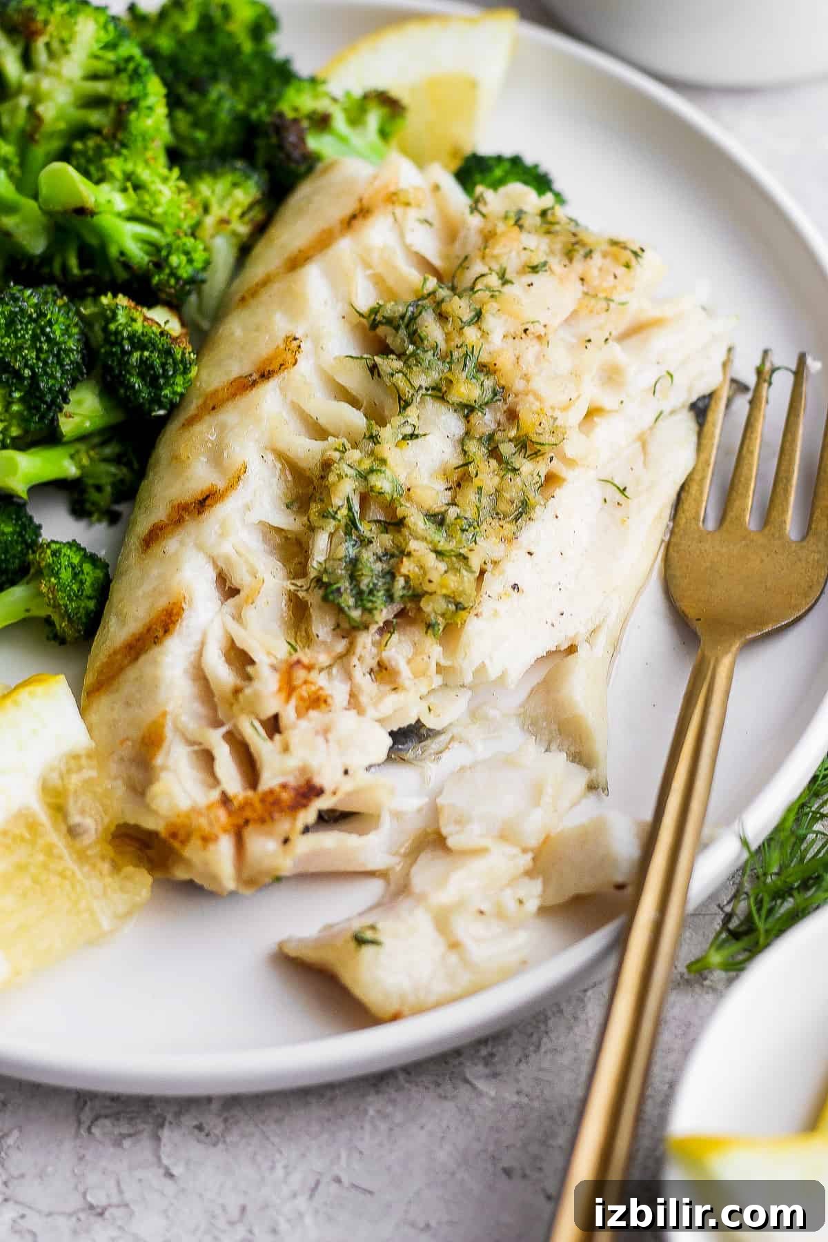 Grilled fish on a plate with broccoli.