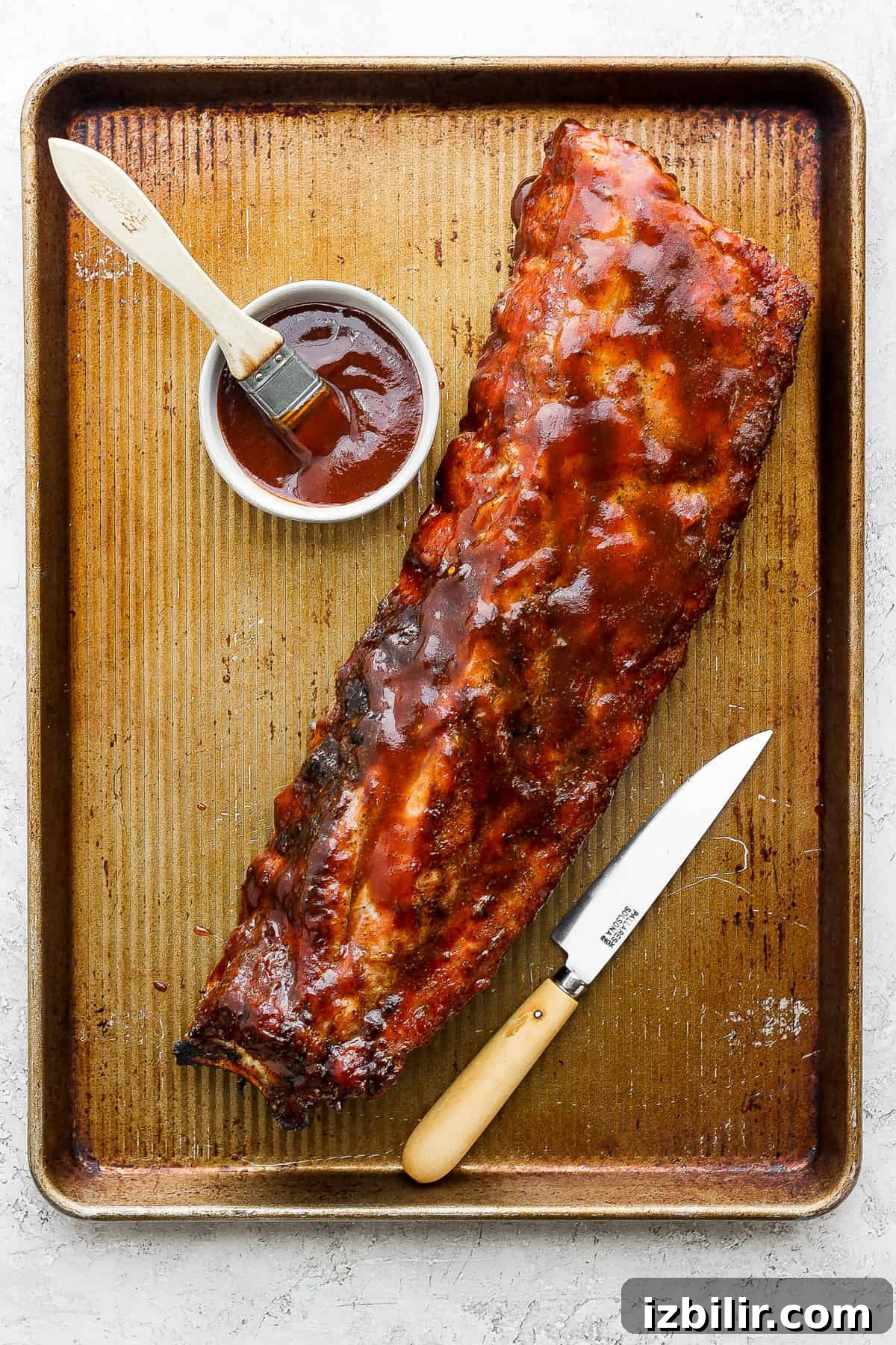 Foolproof Baby Back Ribs: Grill or Oven Recipe 11 a bbq ribs on a tray with ketchup and a knife.