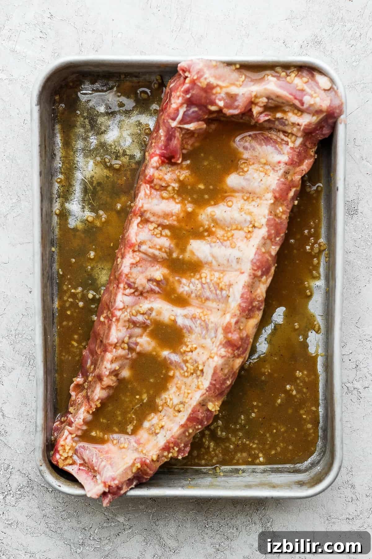 Foolproof Baby Back Ribs: Grill or Oven Recipe 5 A rib in a pan with marinade.
