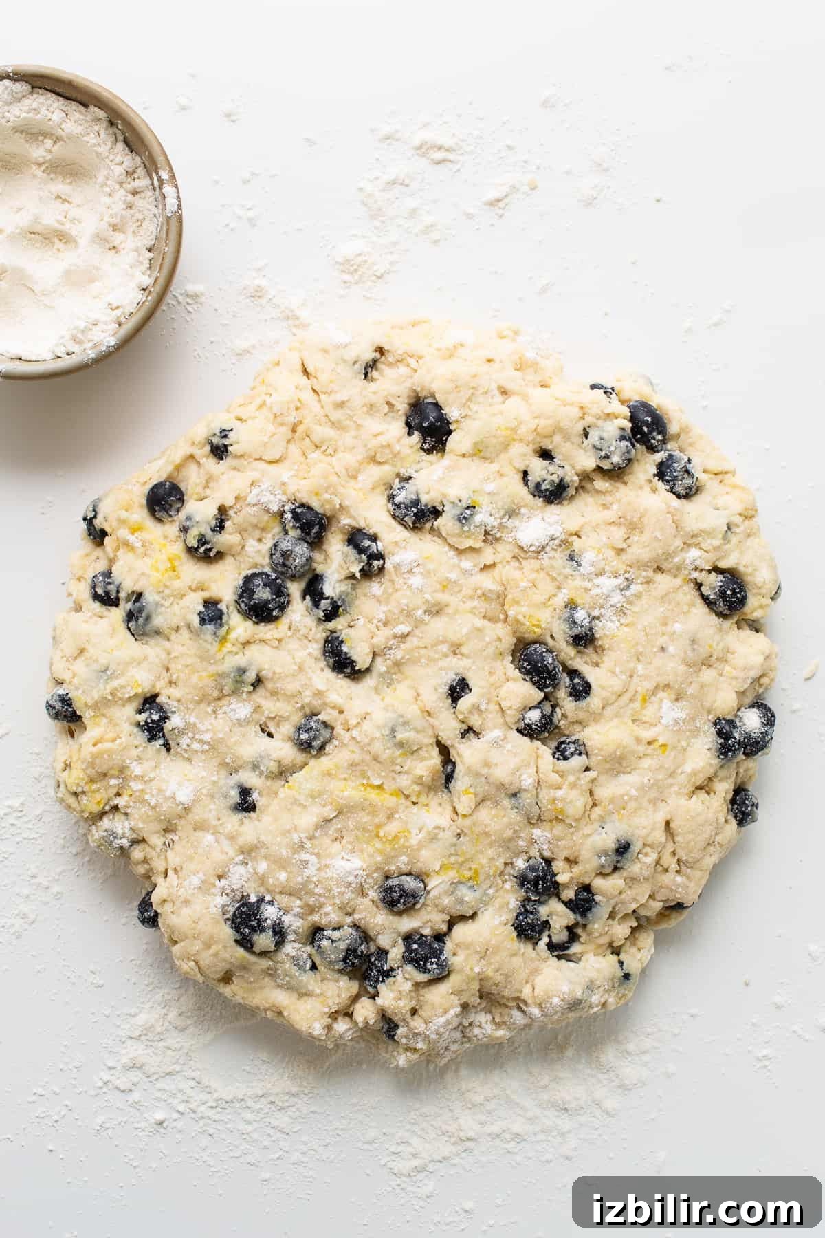 a cookie dough with blueberries and powdered sugar.