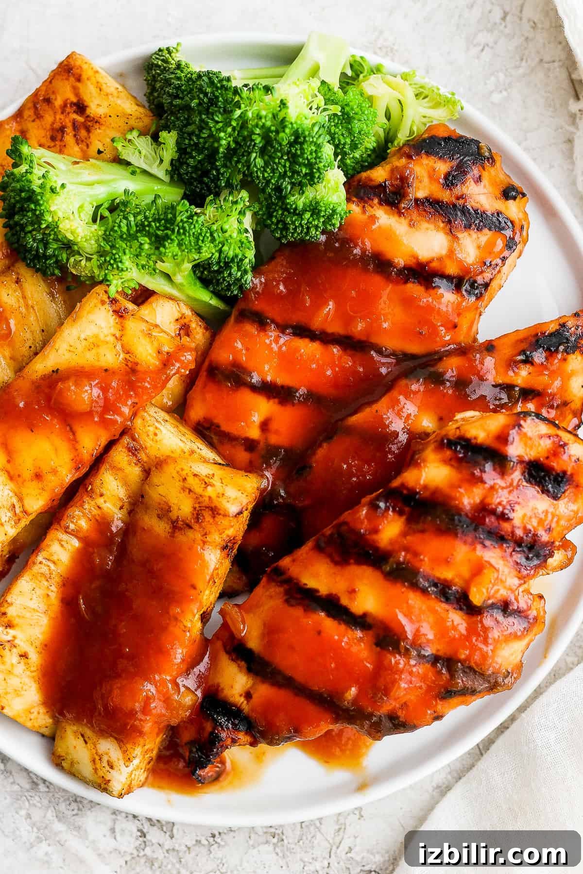 A white plate topped with grilled pineapple chicken and broccoli.