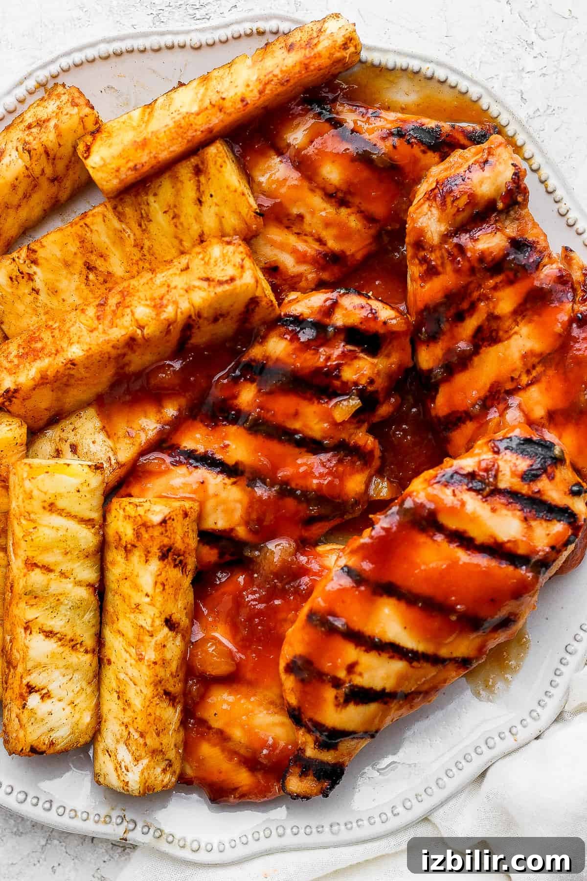 Grilled chicken and pineapple slices on a white plate.