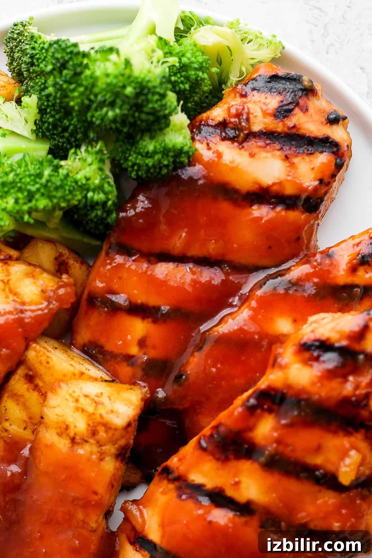 A white plate topped with grilled pineapple chicken and broccoli.