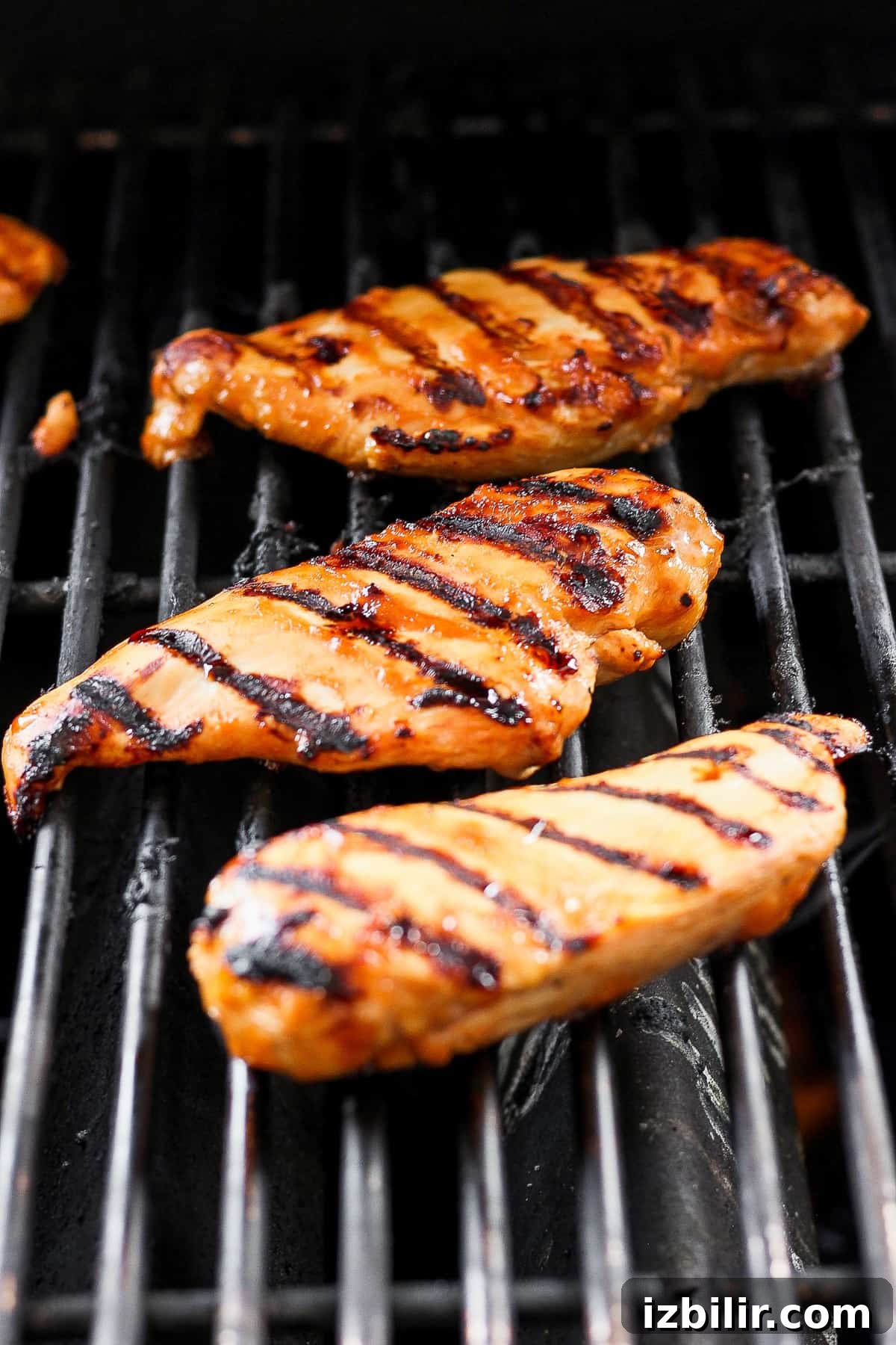 Grilled chicken pieces cooking on a grill.