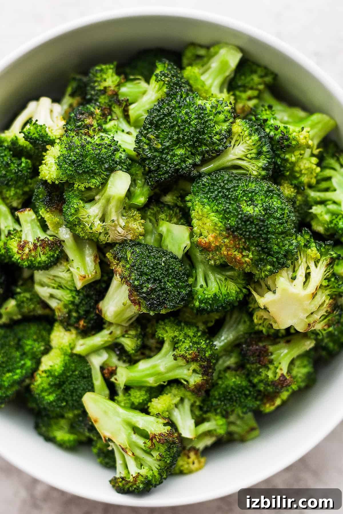 Smoky Grilled Broccoli with Garlic and Lemon 2 a white bowl filled with broccoli on top of a table.