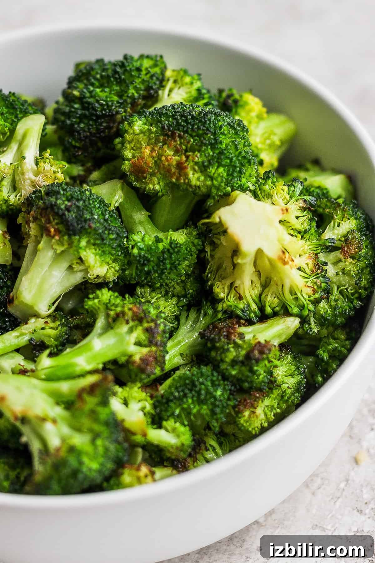 Smoky Grilled Broccoli with Garlic and Lemon 7 a white bowl filled with broccoli on top of a table.