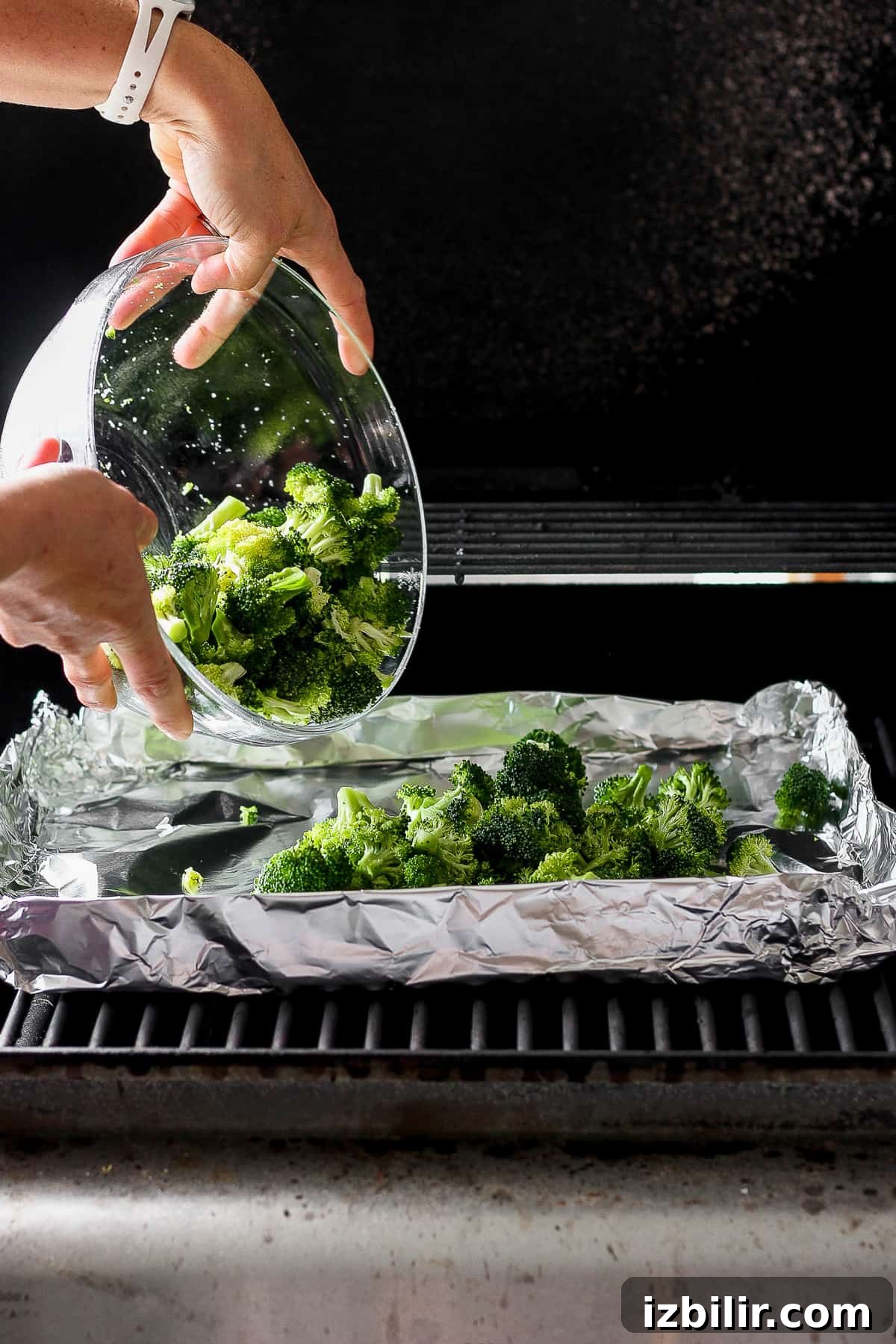 Smoky Grilled Broccoli with Garlic and Lemon 4 a person is putting broccoli in a bowl.