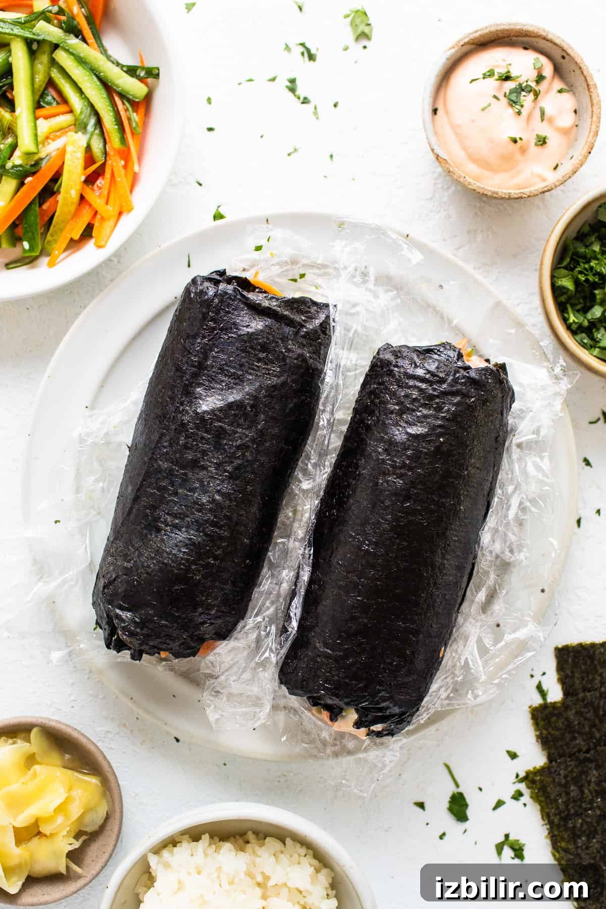 How to Make a Salmon Sushi Burrito at Home 5 a white plate topped with sushi next to bowls of vegetables.