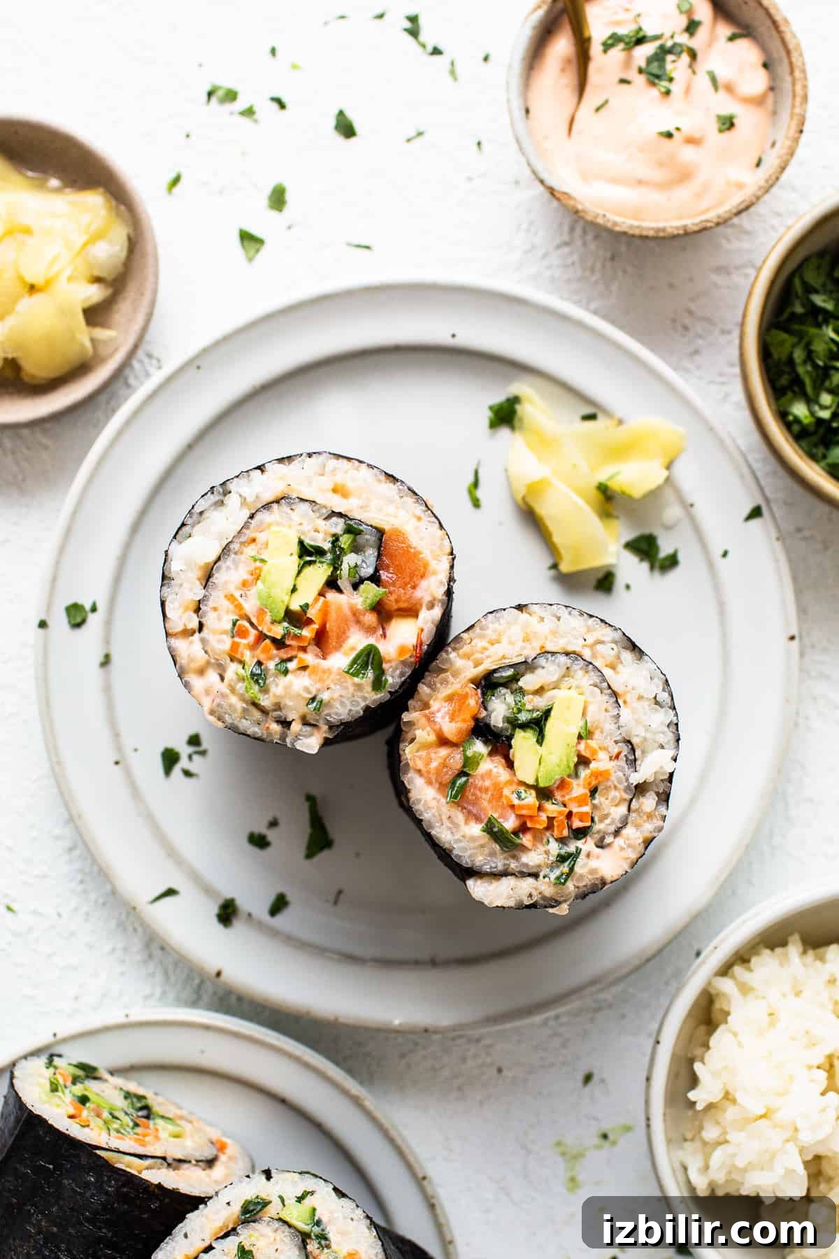 How to Make a Salmon Sushi Burrito at Home 6 a white plate topped with sushi next to bowls of rice.