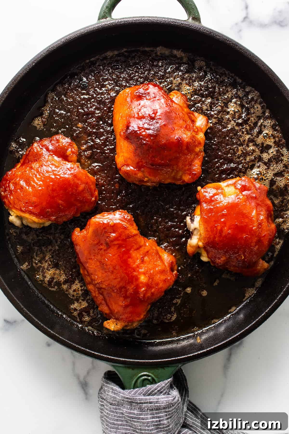 Saucy chicken thighs in a cast iron skillet.