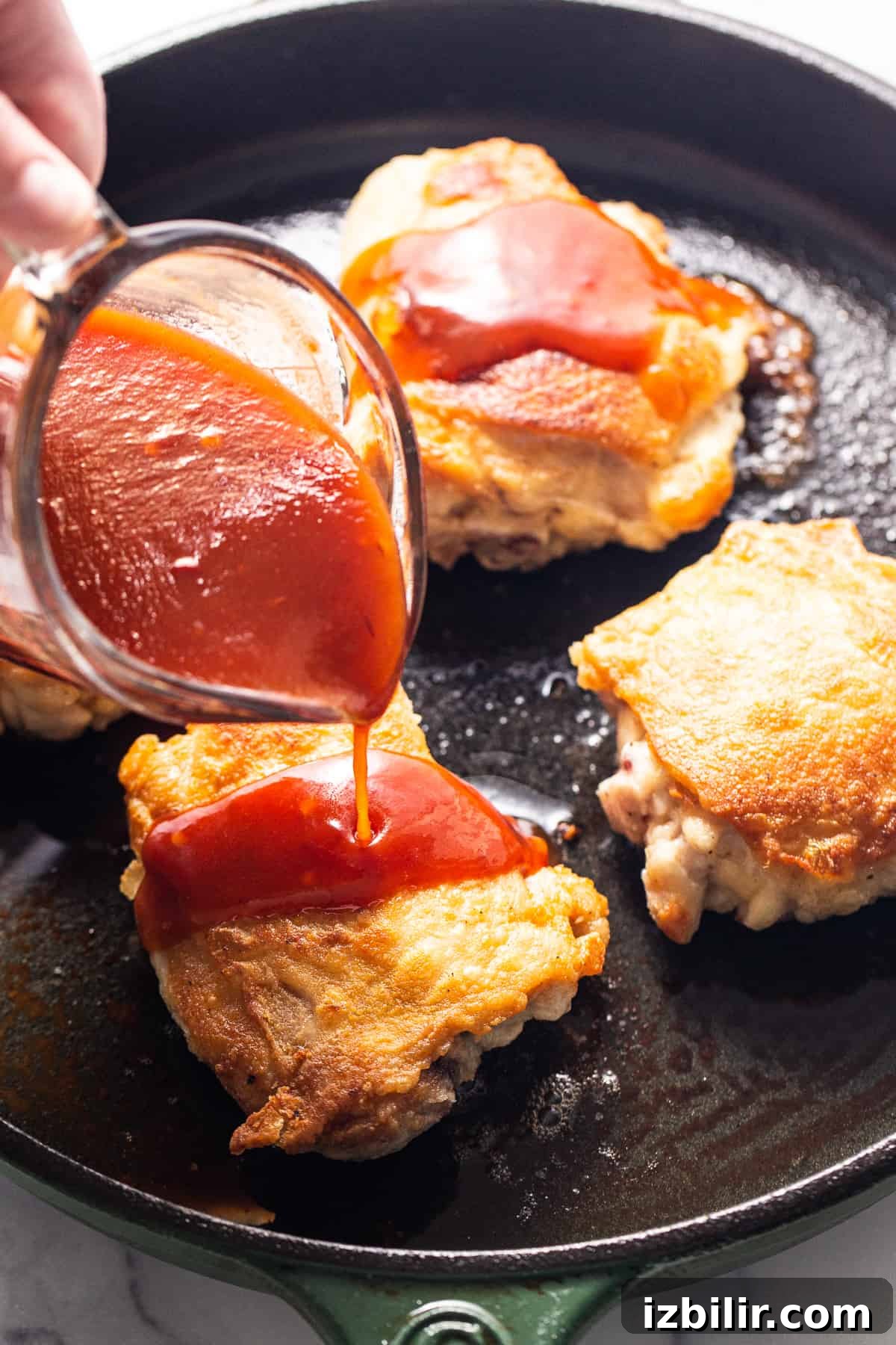 Firecracker Sauce Recipe for Wings, Shrimp and Dips 7 A person pouring ketchup on some food in a skillet.