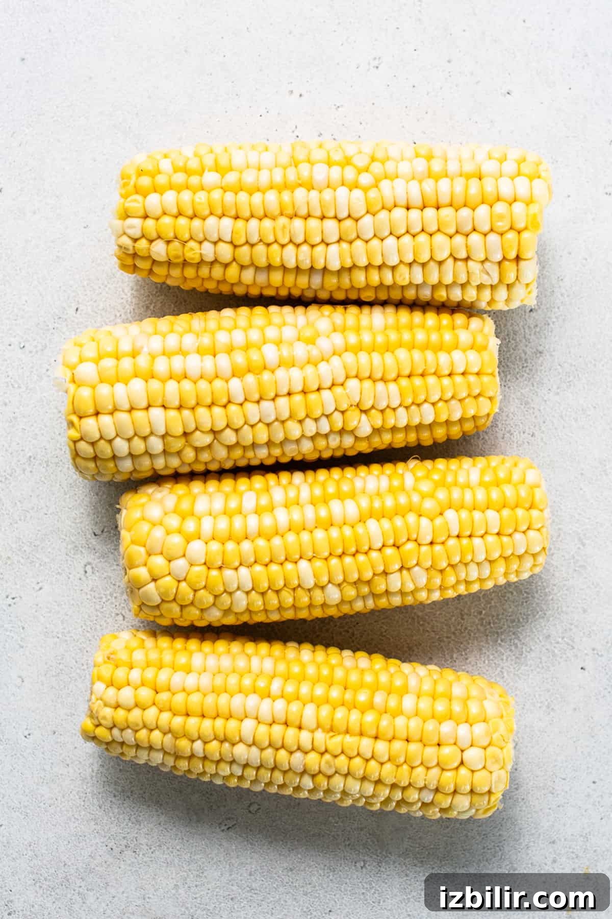 three ears of corn on a white surface.