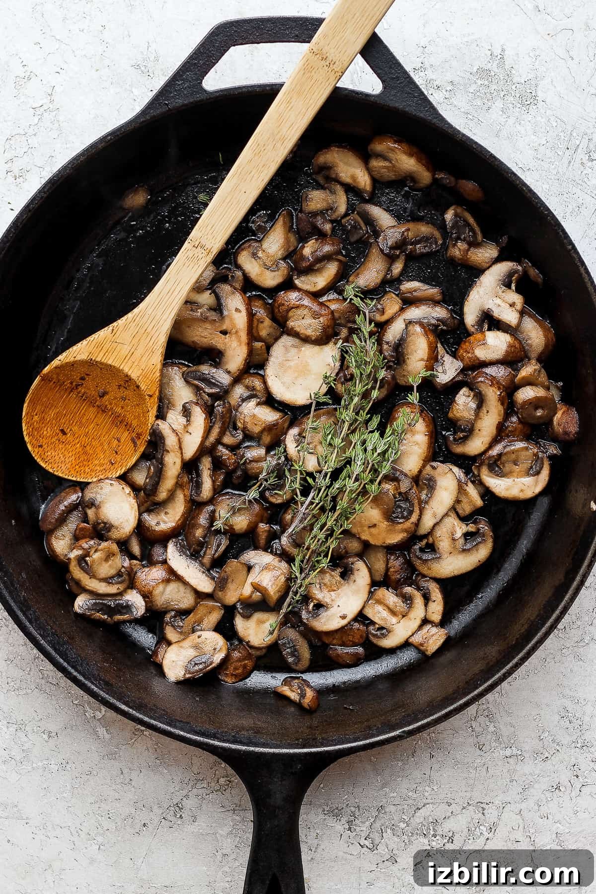 mushrooms in a skillet with a wooden spoon.