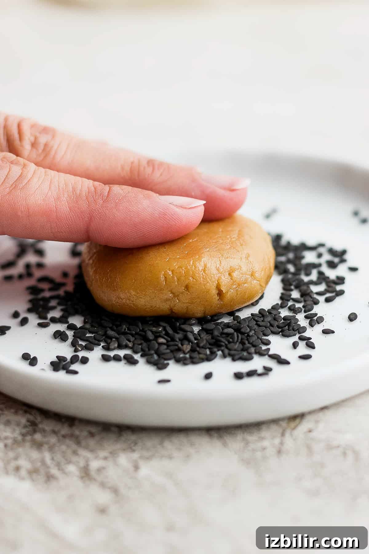 Chewy Tahini Cookies Recipe 5 a hand is holding a cookie with sesame seeds on it.