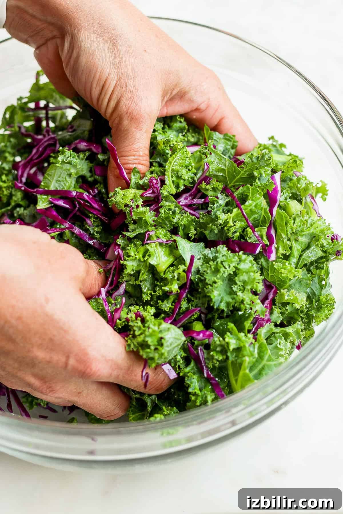 A person putting kale into a bowl.