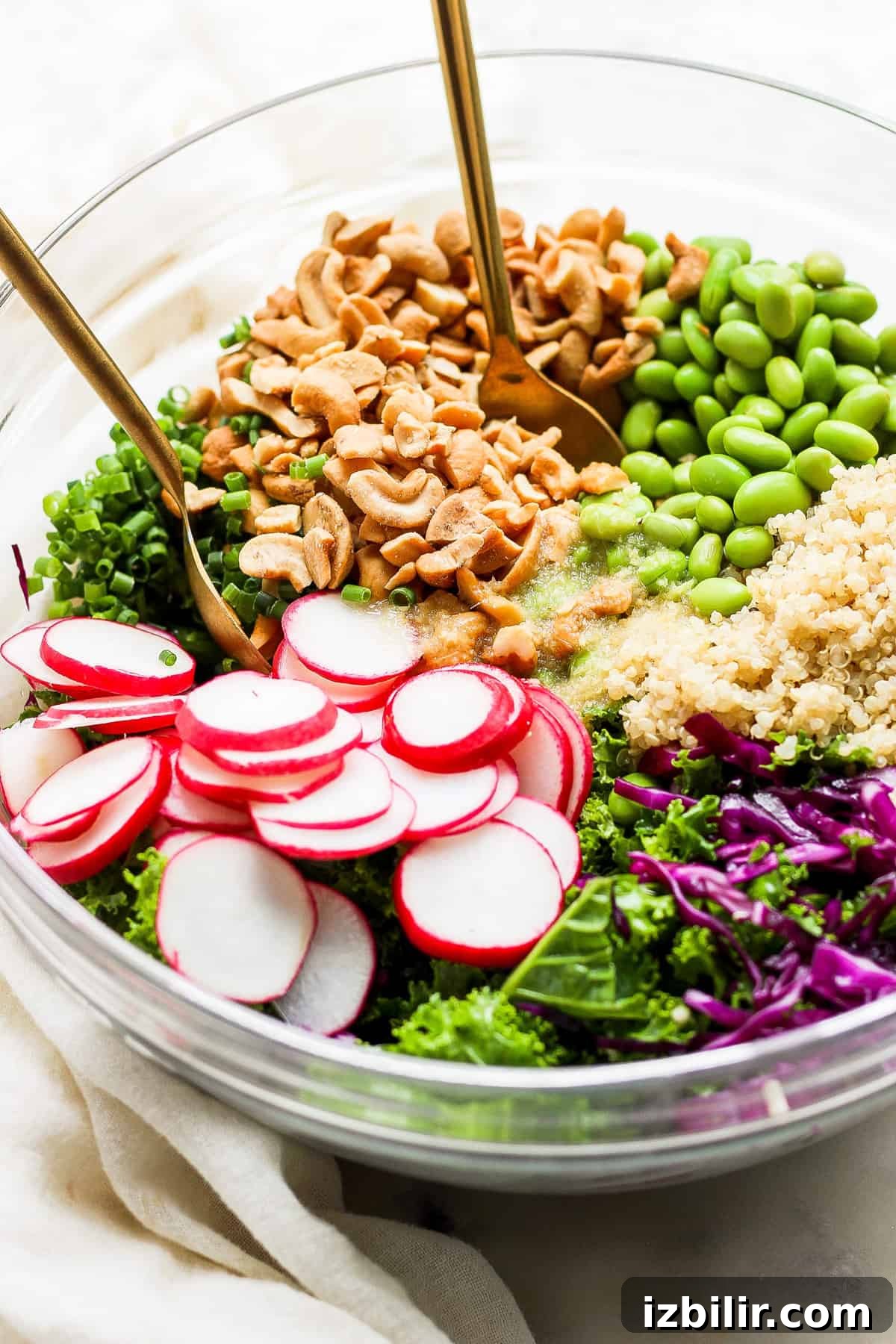 A bowl filled with greens, radishes, and cashews.