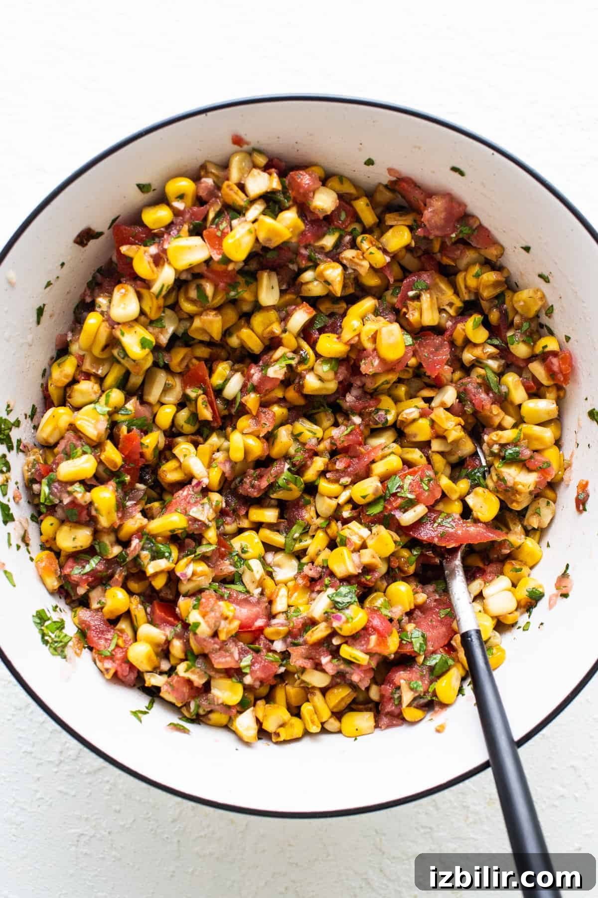 Corn salsa in a white bowl with a fork.
