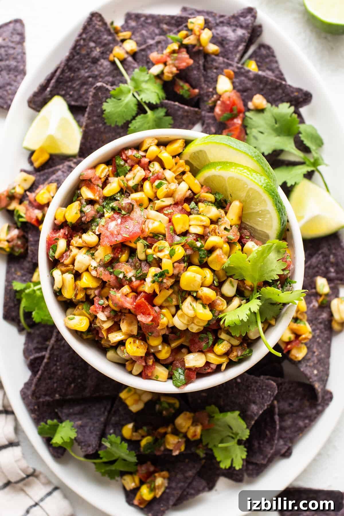 Mexican corn salsa on a white plate with tortilla chips.