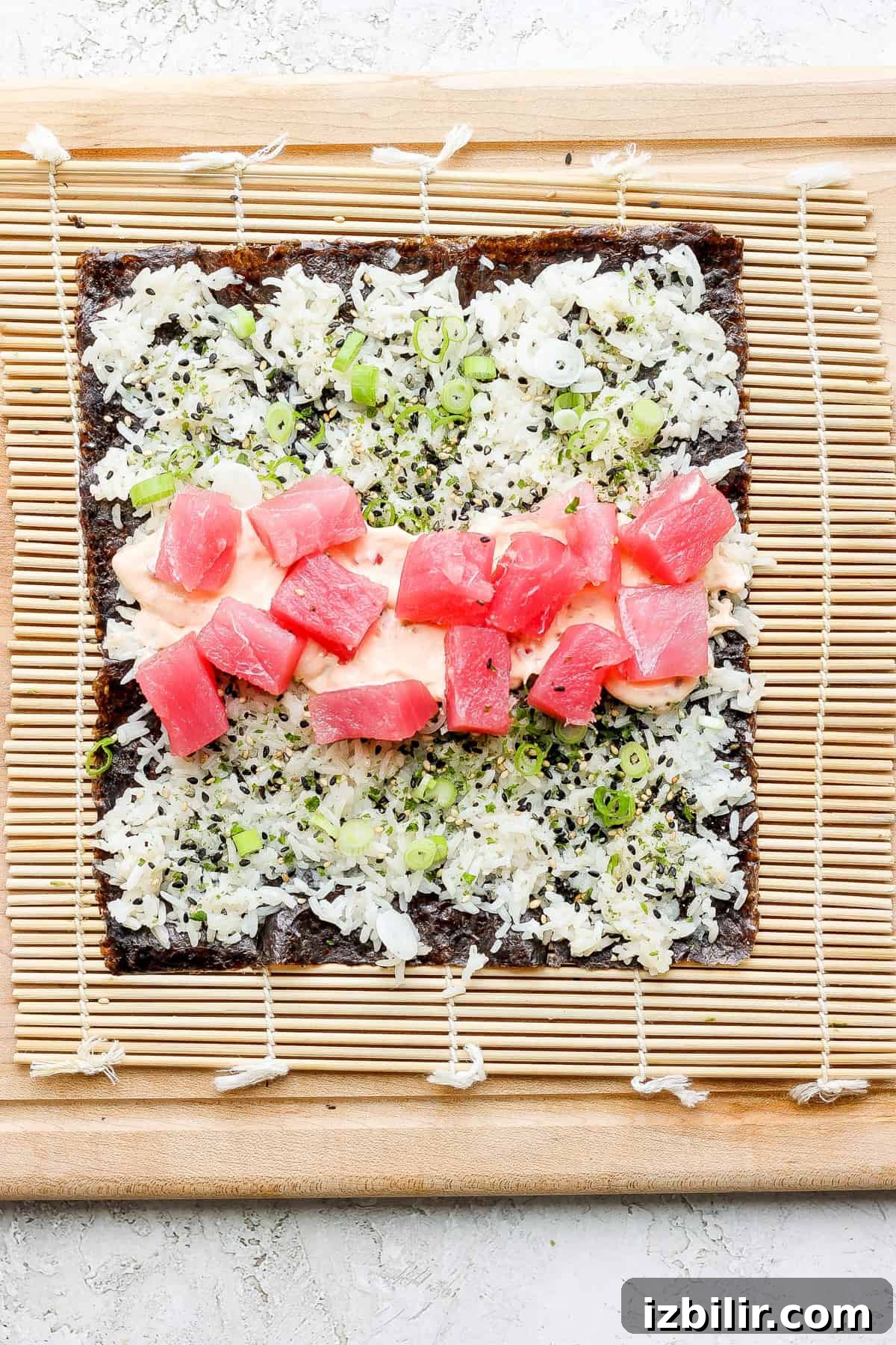 Spicy Tuna Roll Recipe: How to Make at Home 5 a piece of sushi on a wooden cutting board.