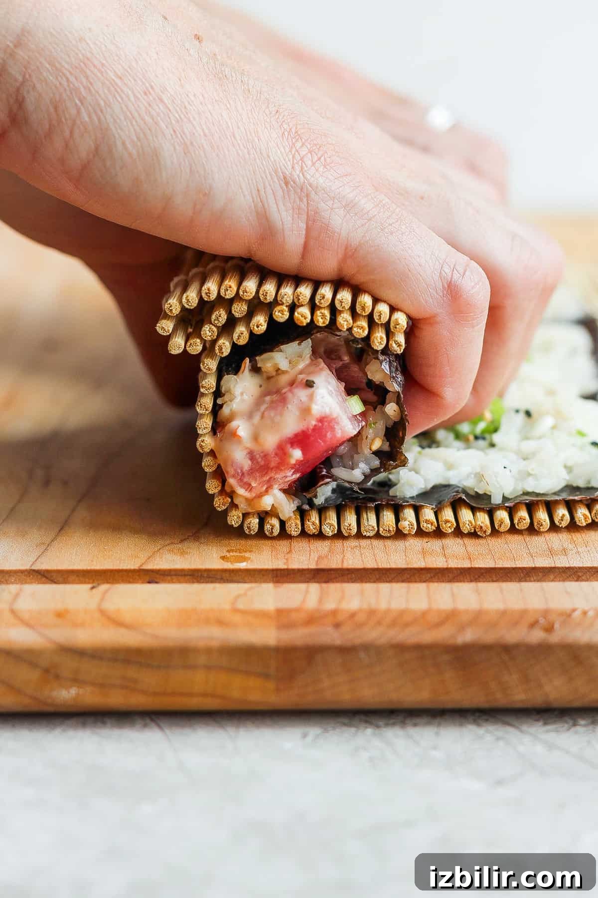 Spicy Tuna Roll Recipe: How to Make at Home 6 a person making a sandwich on a wooden cutting board.