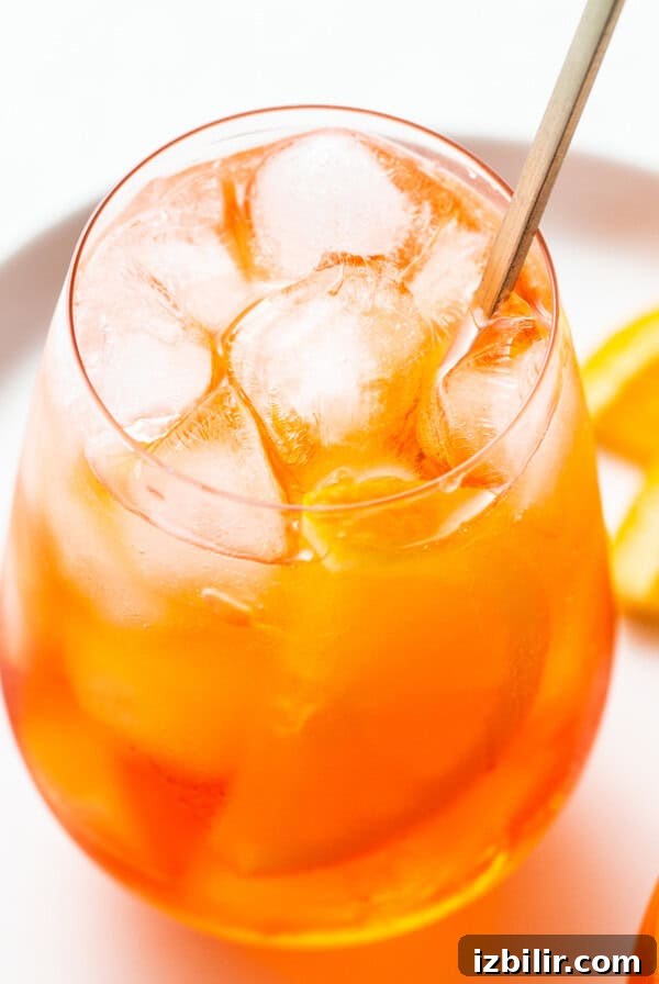Aperol spritz in a glass with a straw.