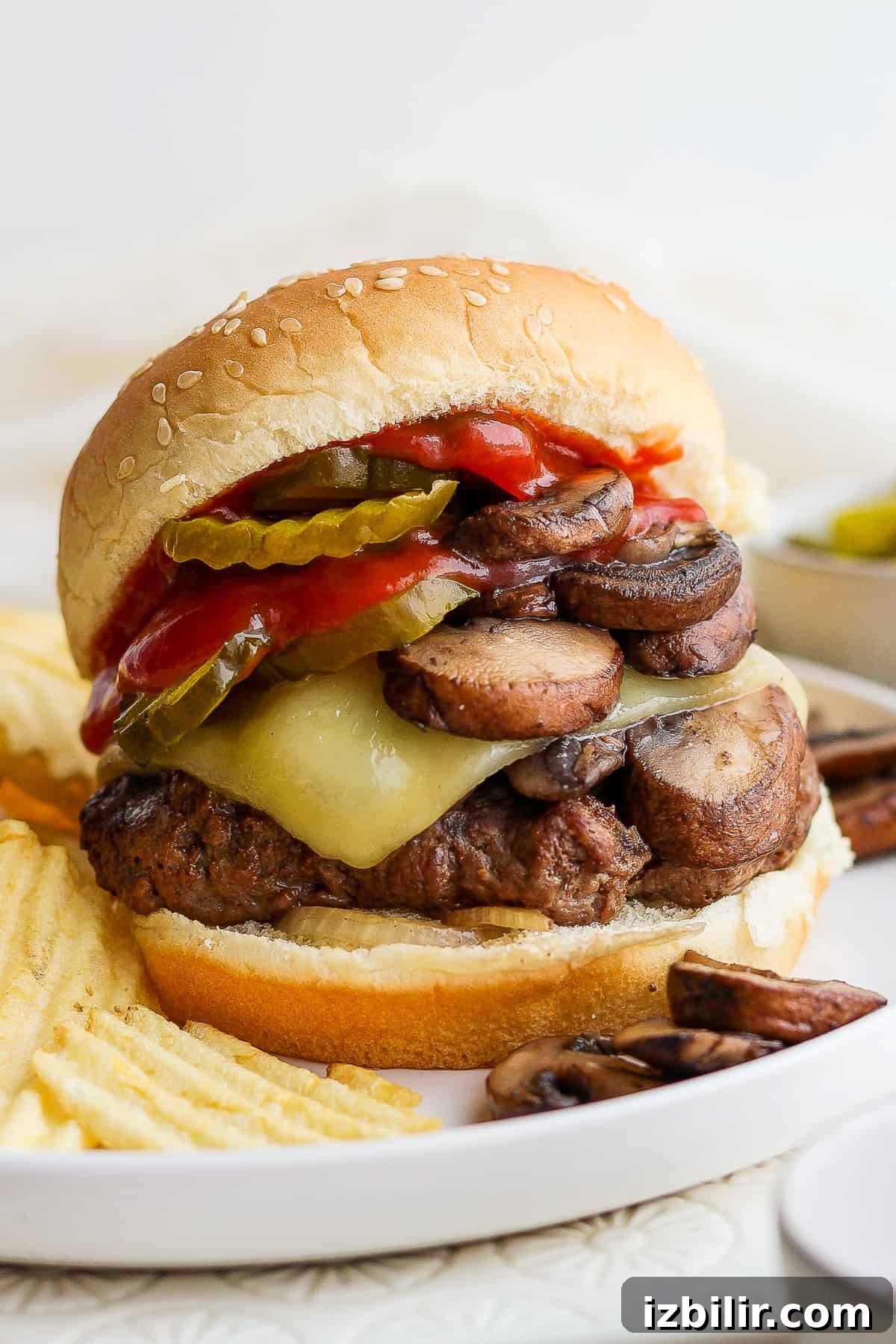 Grilled Mushroom Swiss Burger Recipe 2 a burger with mushrooms and peppers on a plate.
