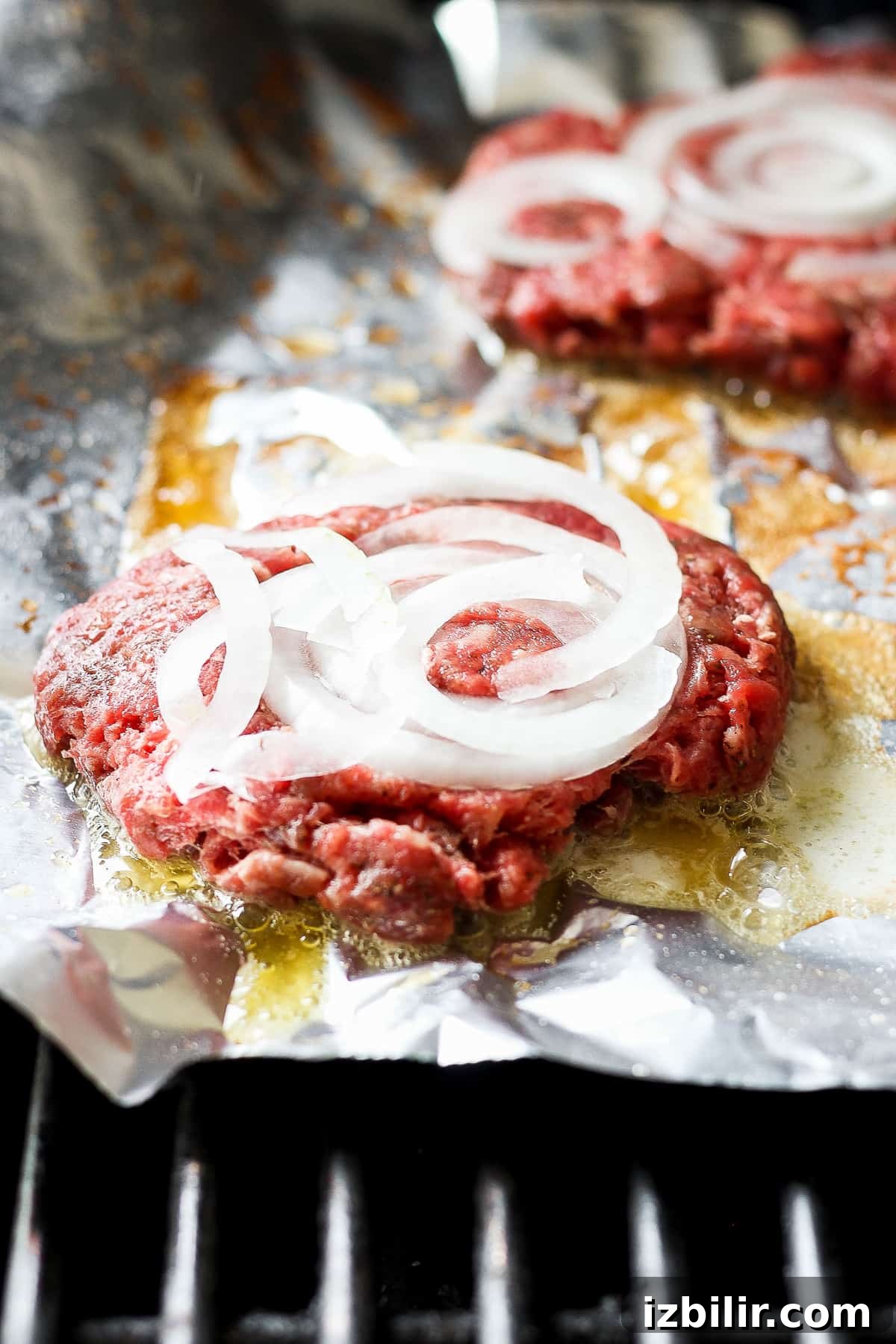 Grilled Mushroom Swiss Burger Recipe 4 beef burgers with onions on foil.