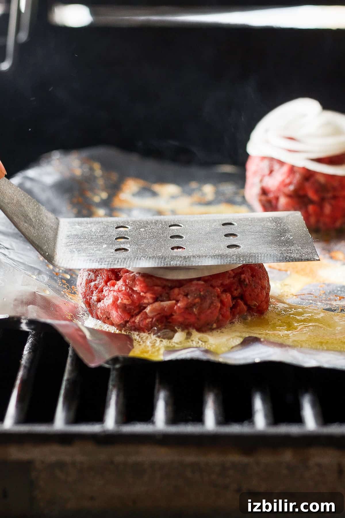 Grilled Mushroom Swiss Burger Recipe 5 a person is slicing burgers on a grill.